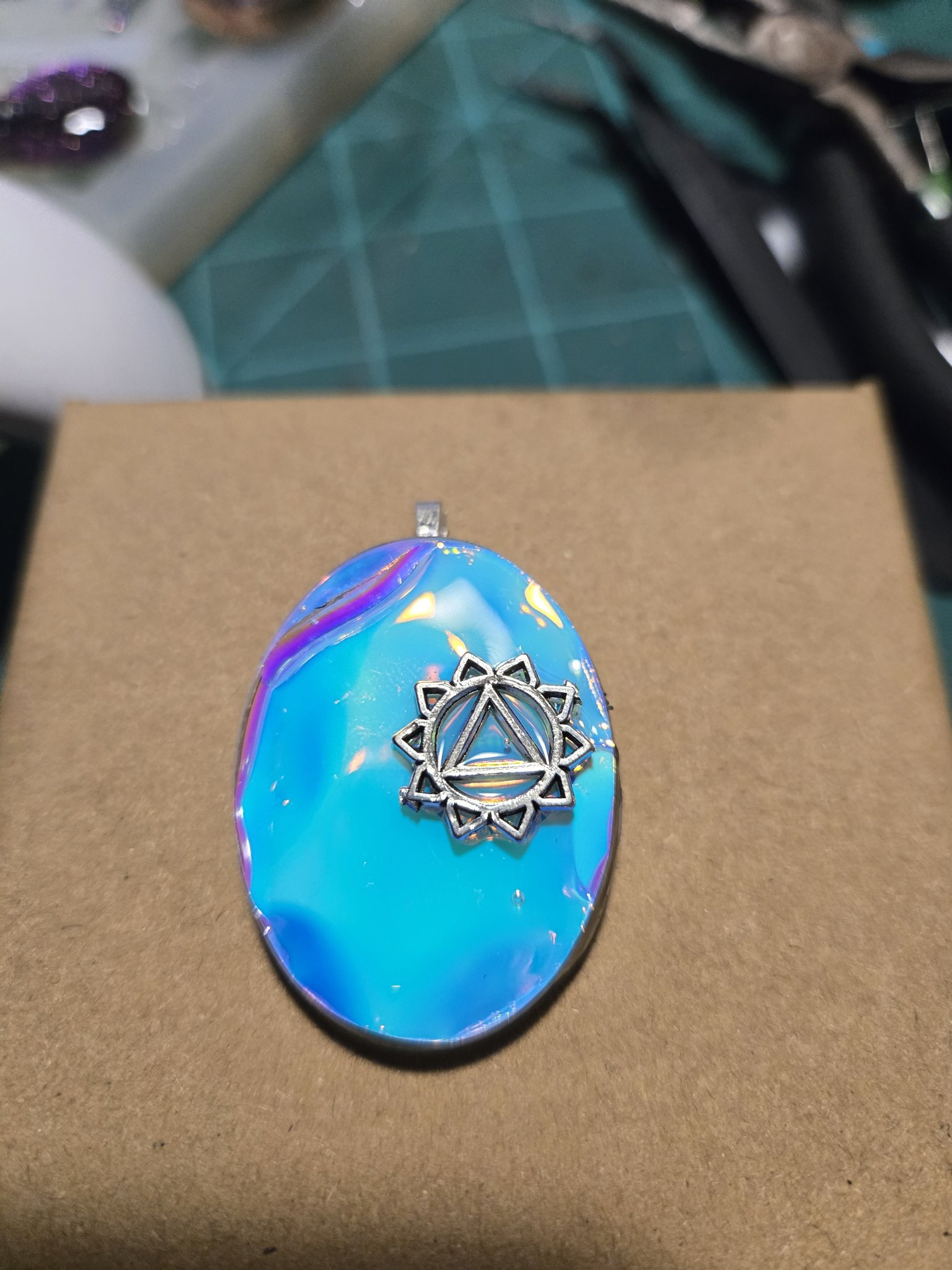 Blue-to-purple holographic oval pendant with a silver-tone mandala charm