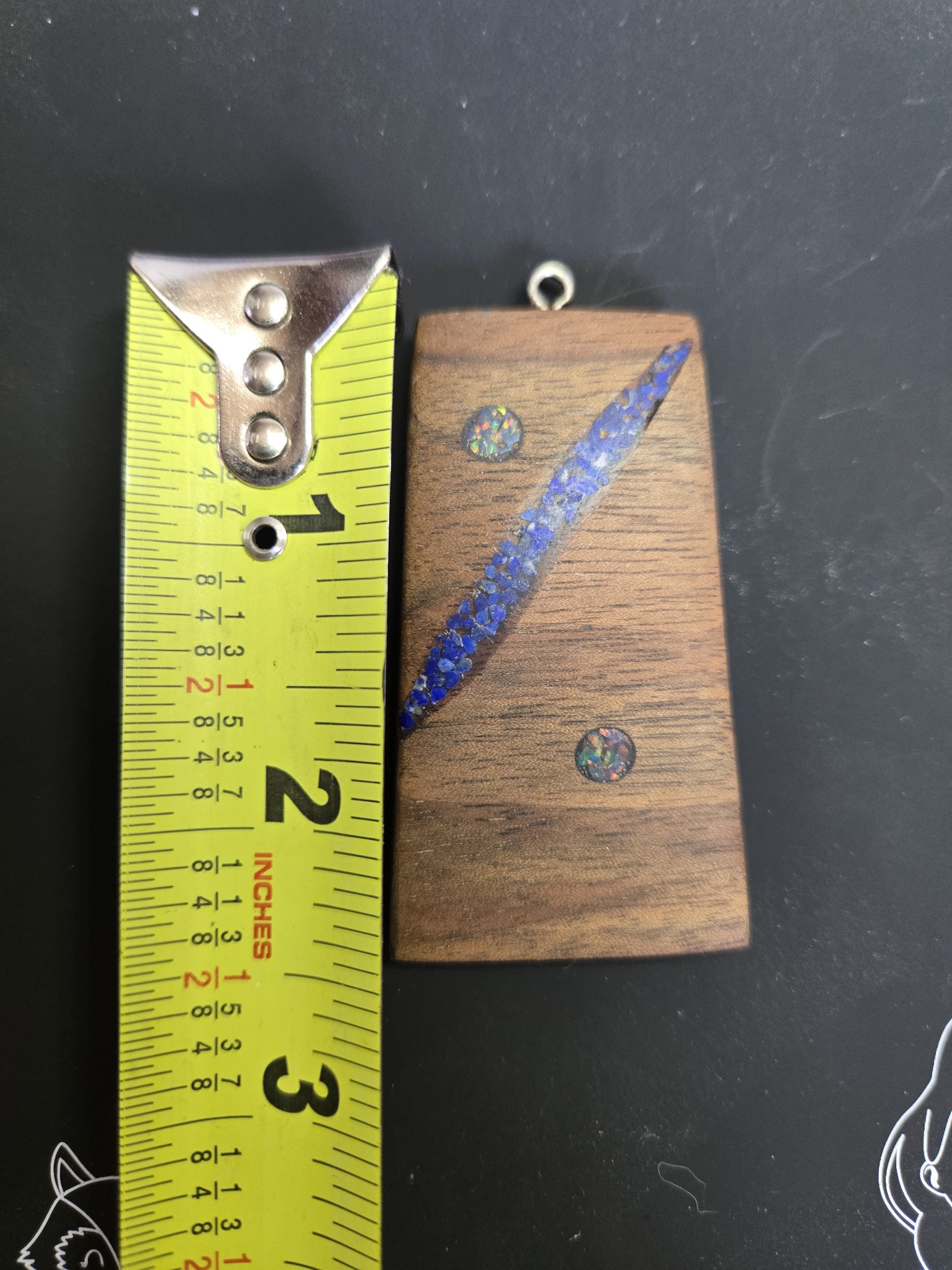 Walnut lapis and opal pendant beside a tape measure showing it is about two and a half inches long