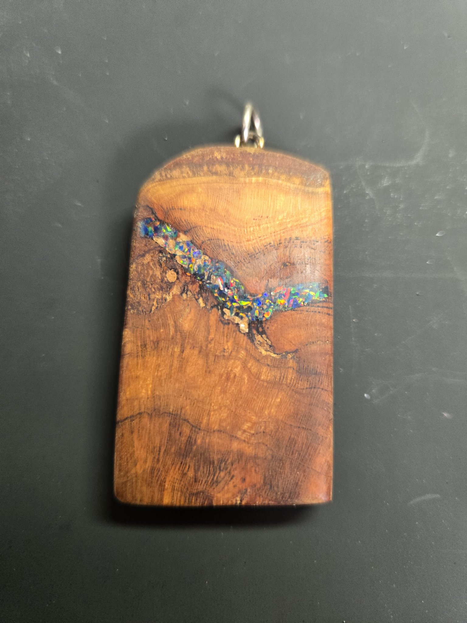 Close-up front view of a rectangular spalted maple pendant with a diagonal black fire opal inlay
