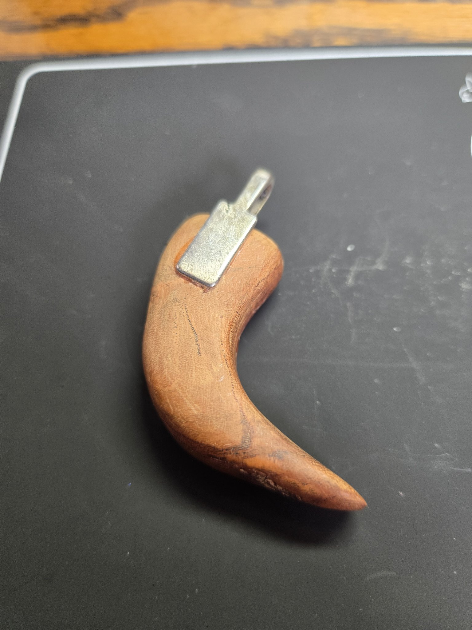 Back of the maple bear claw pendant showing the natural wood grain and silver-tone bail
