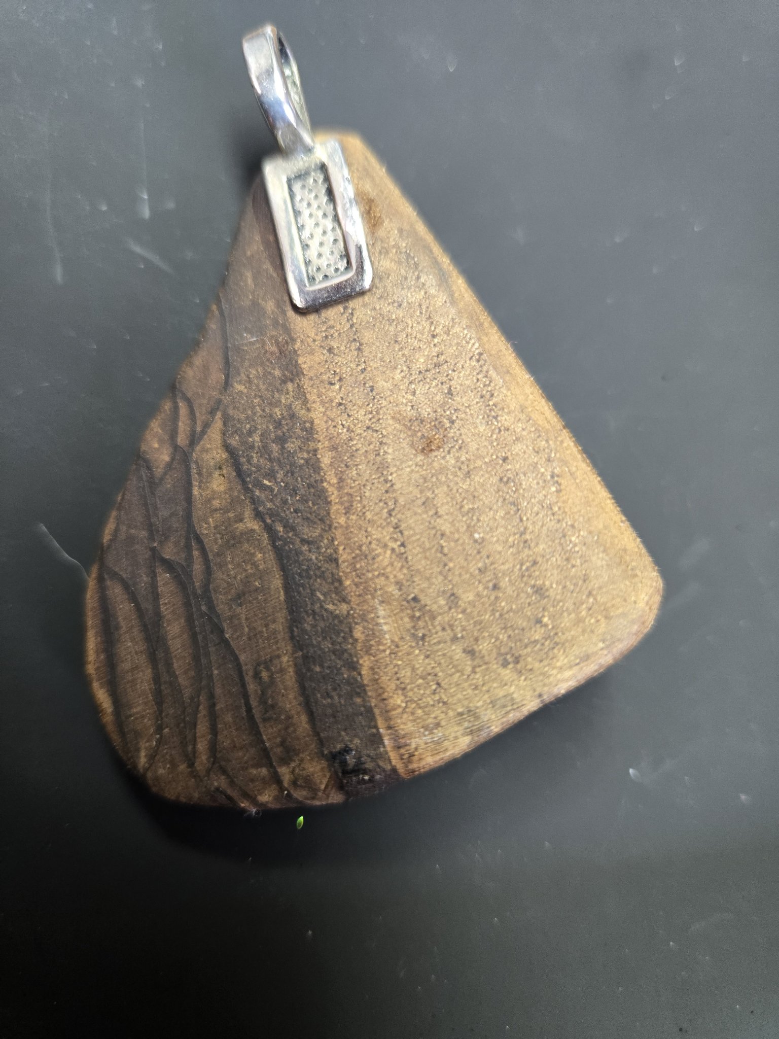 Back of the figured maple pendant showing the natural wood grain and silver-tone bail