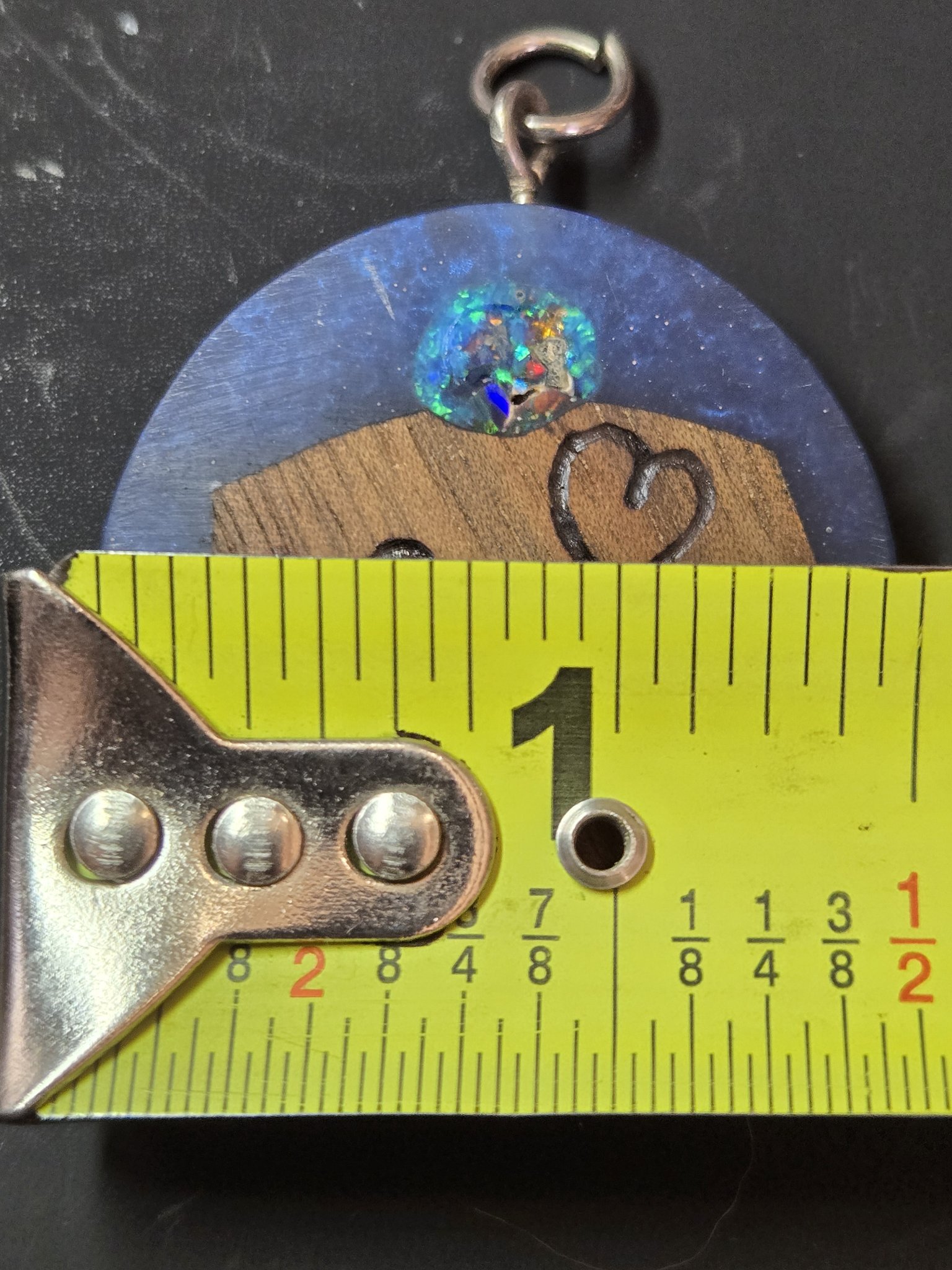 Close view of the Love pendant against a tape measure