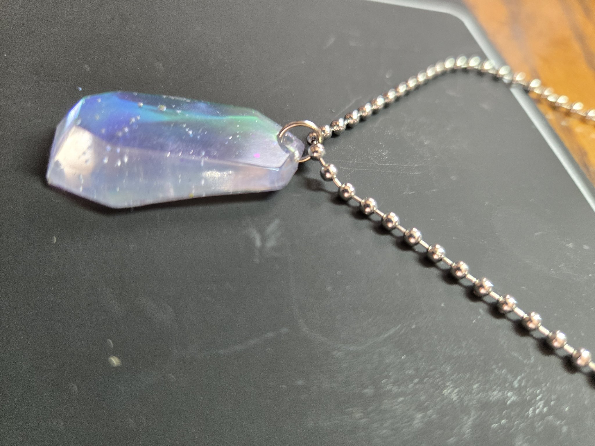 Side angle of the faceted holographic resin crystal pendant and silver-tone ball chain