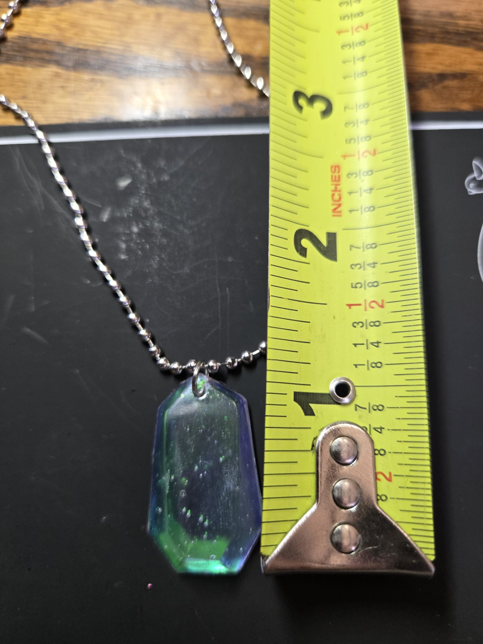 Holographic resin crystal pendant beside a tape measure showing it is about two inches long