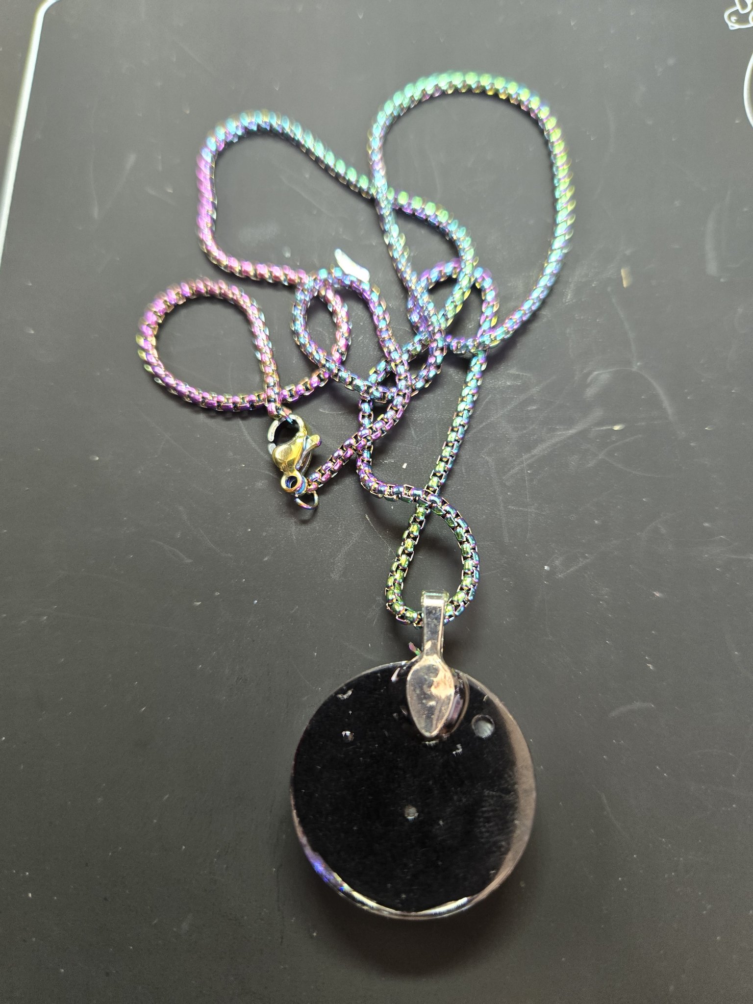 Back of the round holographic resin pendant with the rainbow iridescent chain