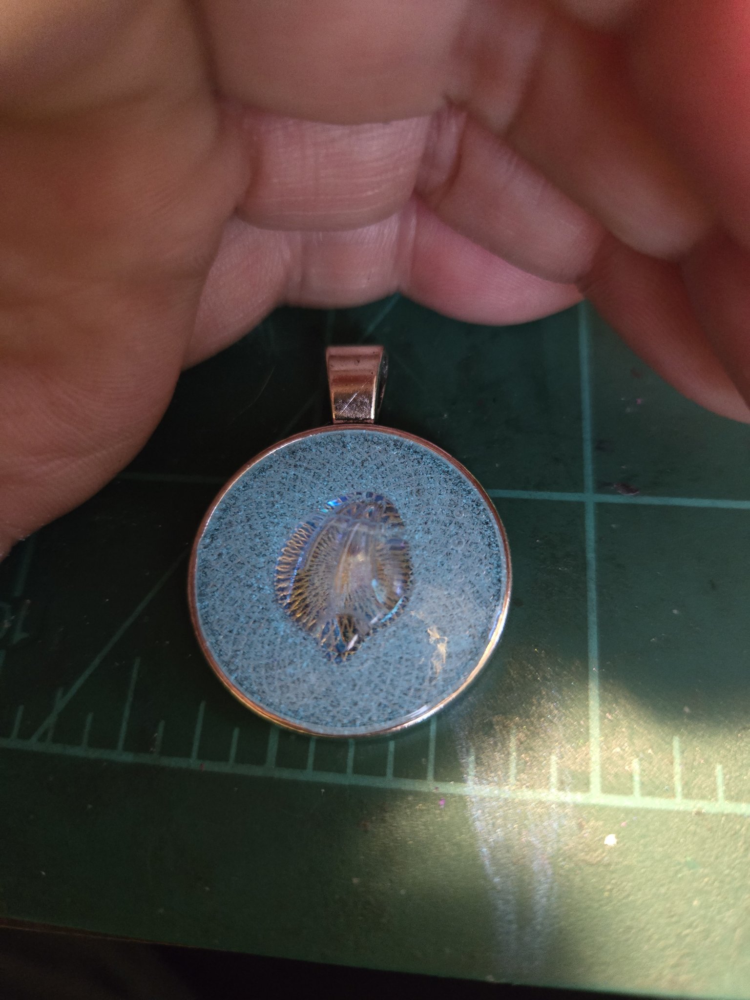 Unlit view of the round resin shell pendant in its silver-tone frame
