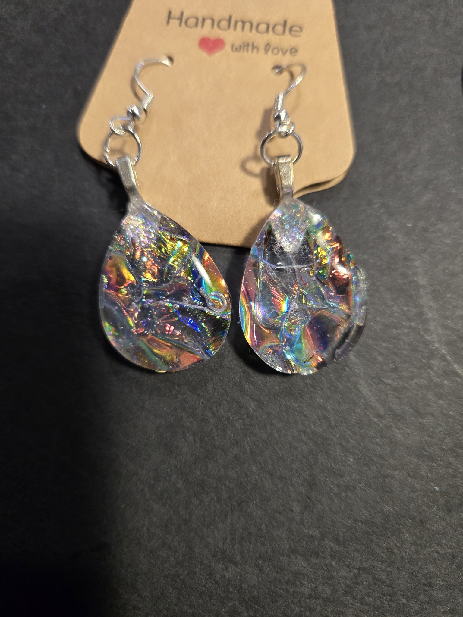 Pair of clear holographic acrylic teardrop earrings with rainbow shimmer displayed on a handmade jewelry card