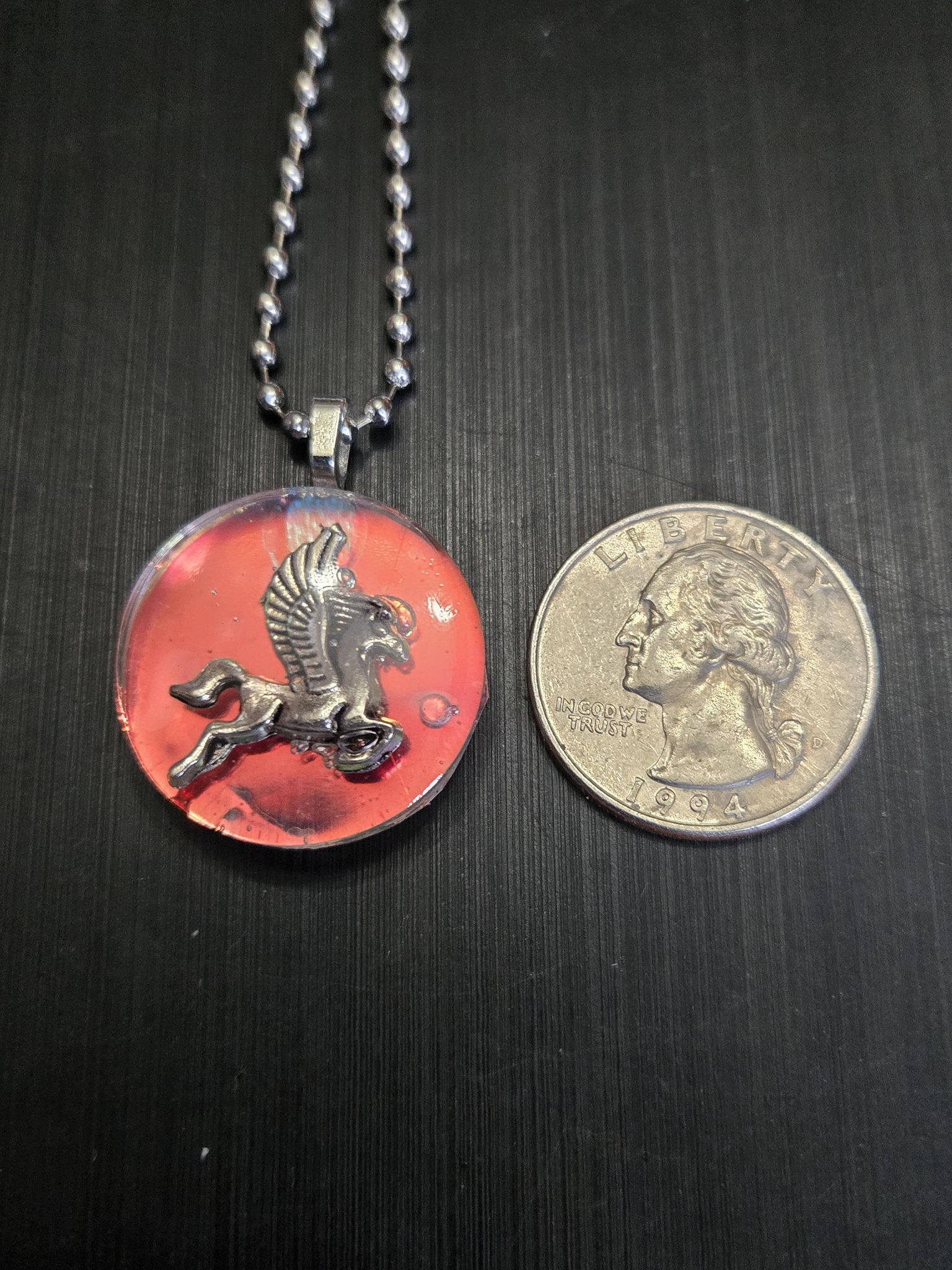 Holographic pegasus pendant beside a quarter showing it is approximately one and a half inches across