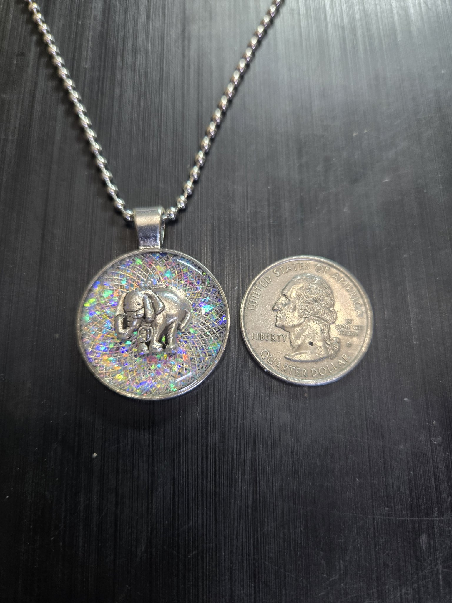Elephant pendant beside a quarter showing it is approximately one and a half inches across