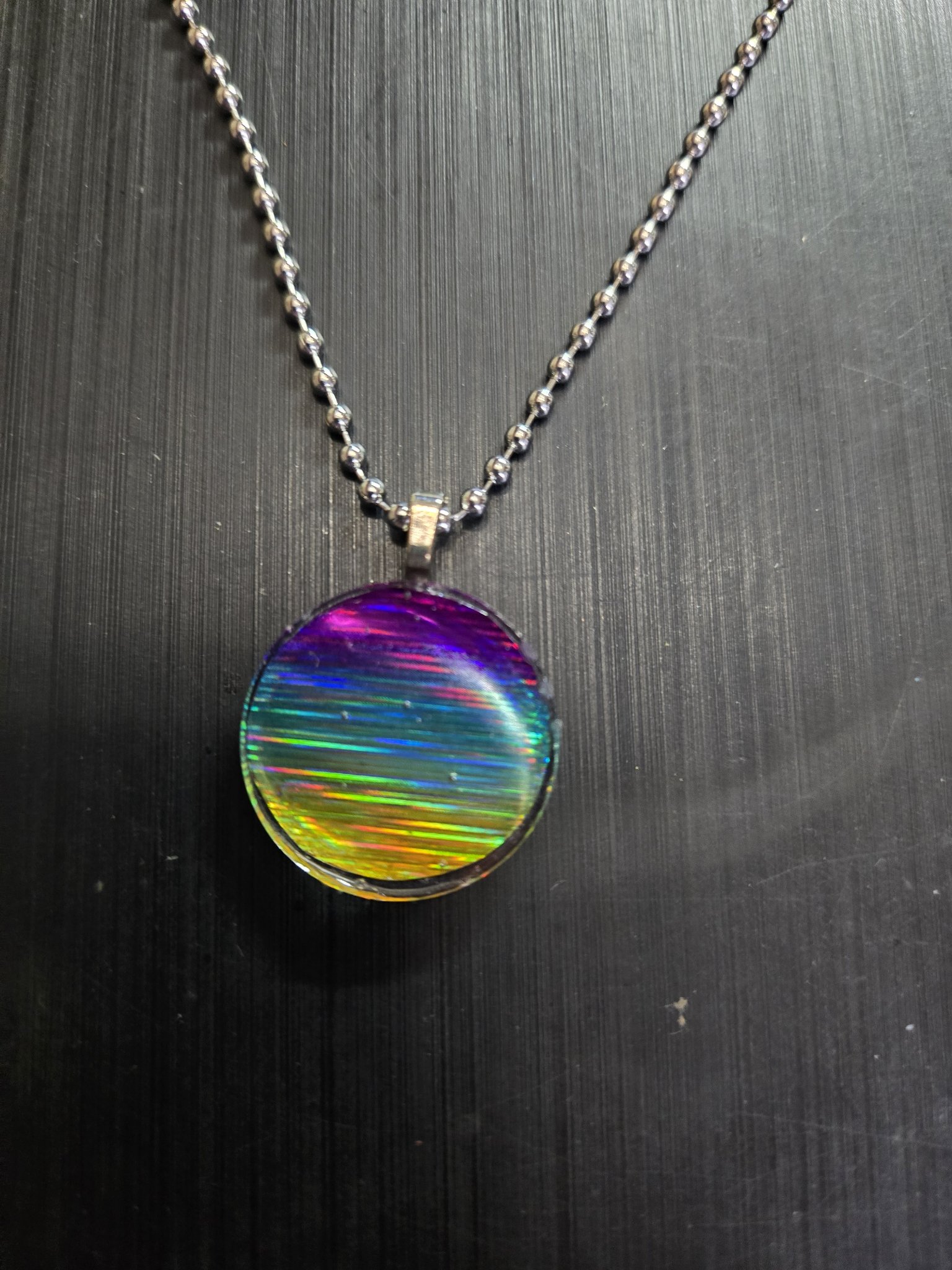 Front view of the round holographic rainbow resin pendant on its 22-inch ball chain