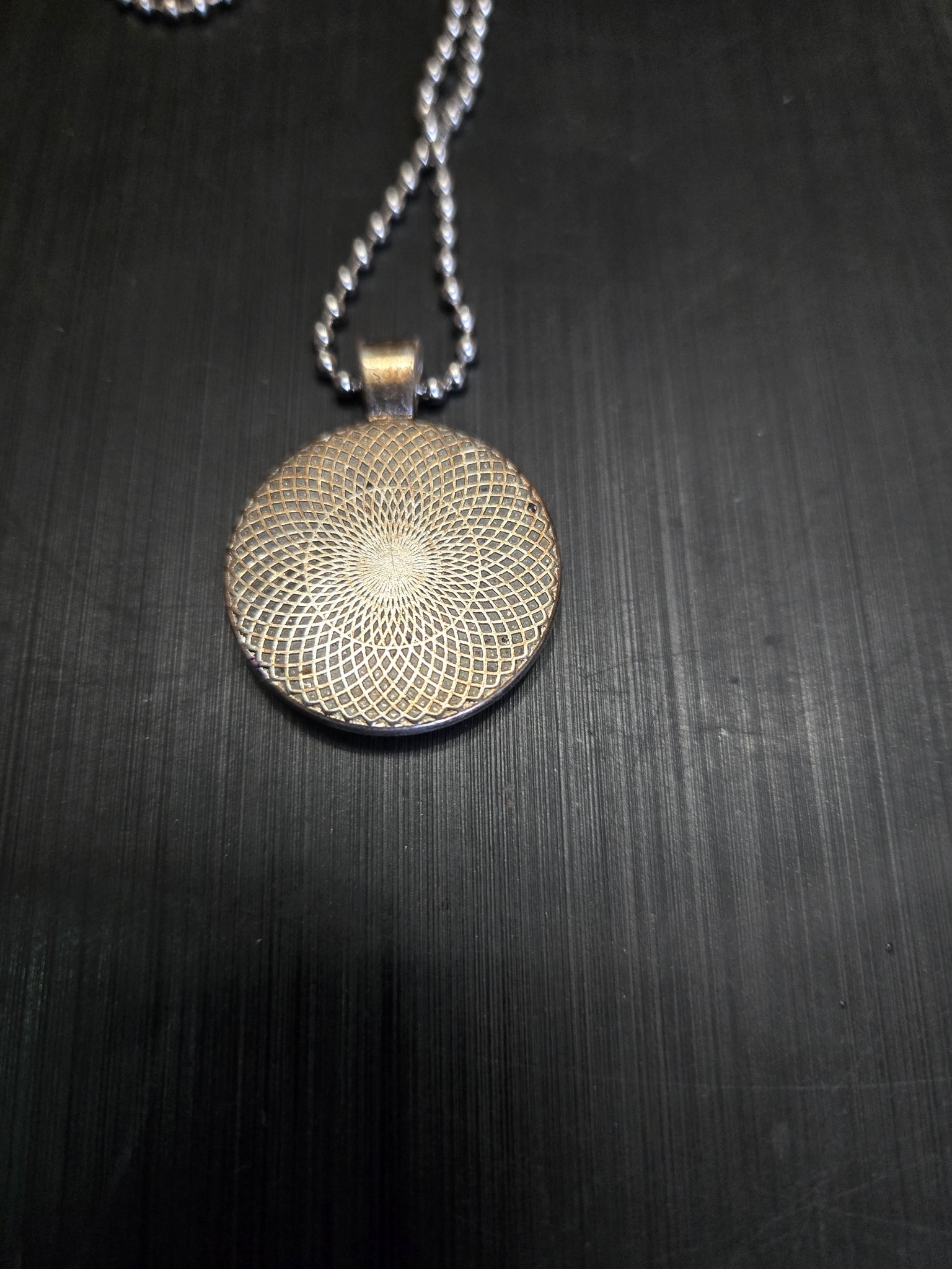 Back view of the pendant showing the silver-tone metal mandala pattern
