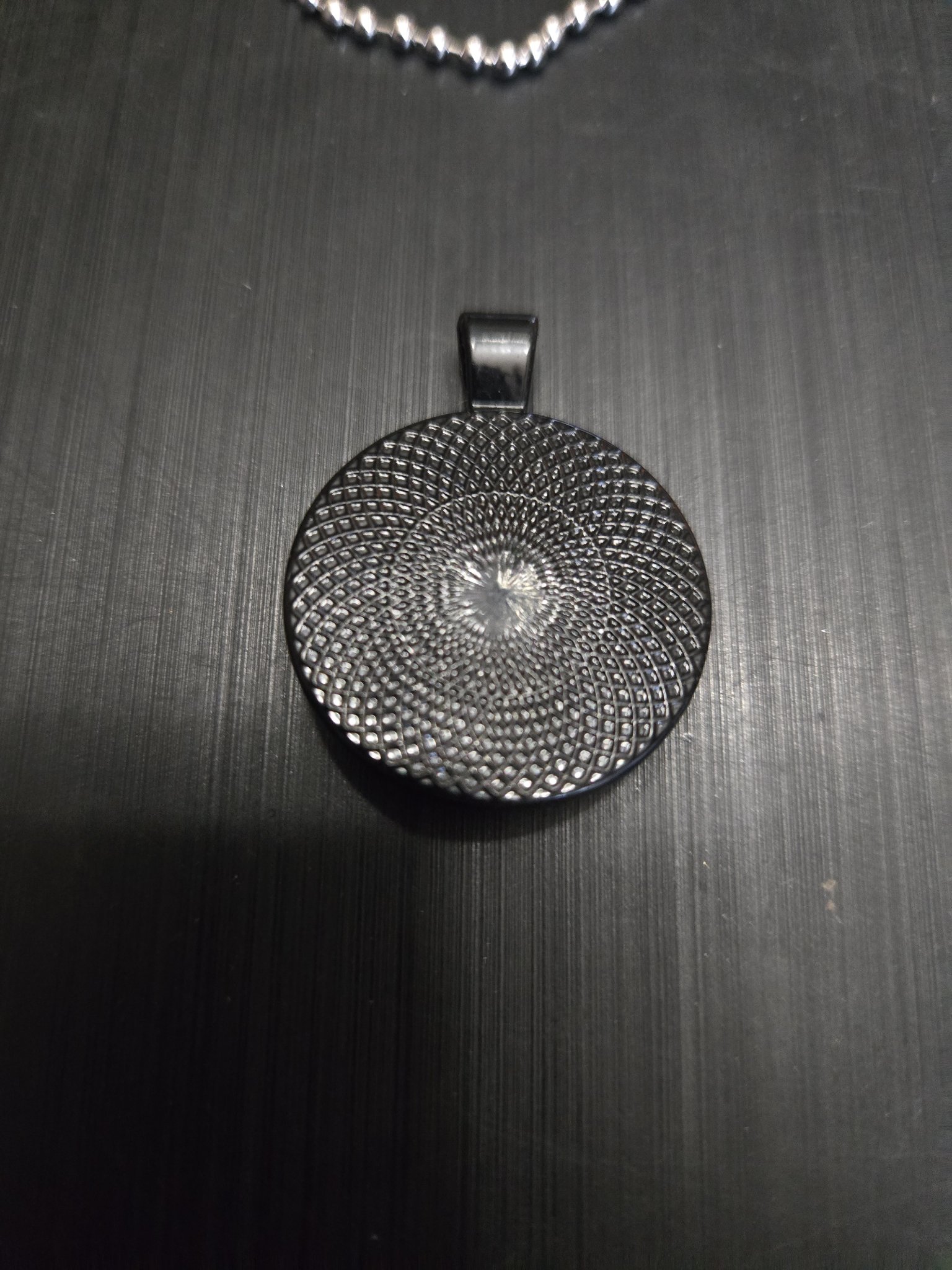 Back view of the football pendant showing the black metal mandala pattern