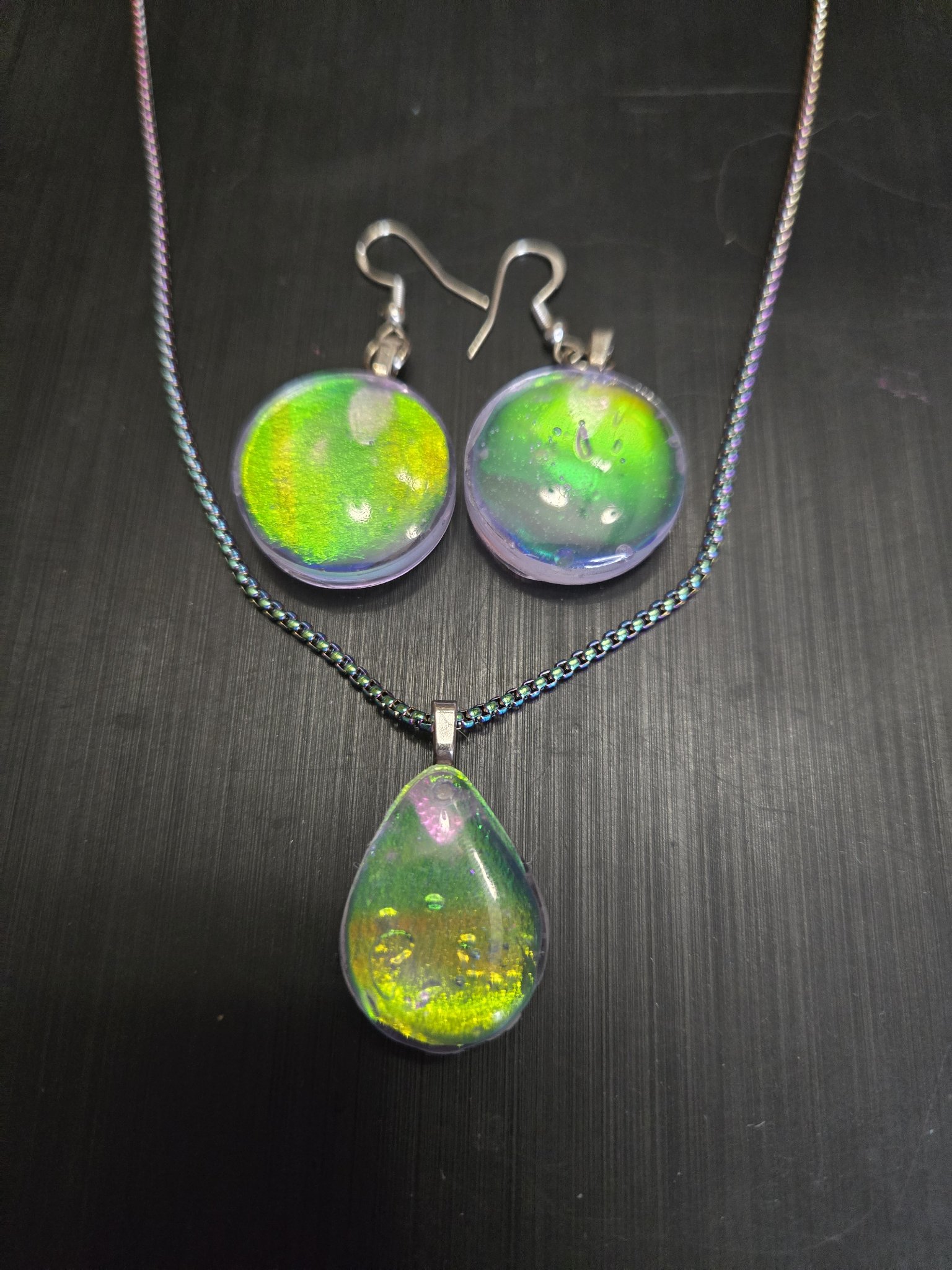 Matching set of round green-gold holographic earrings and a teardrop pendant on a rainbow chain