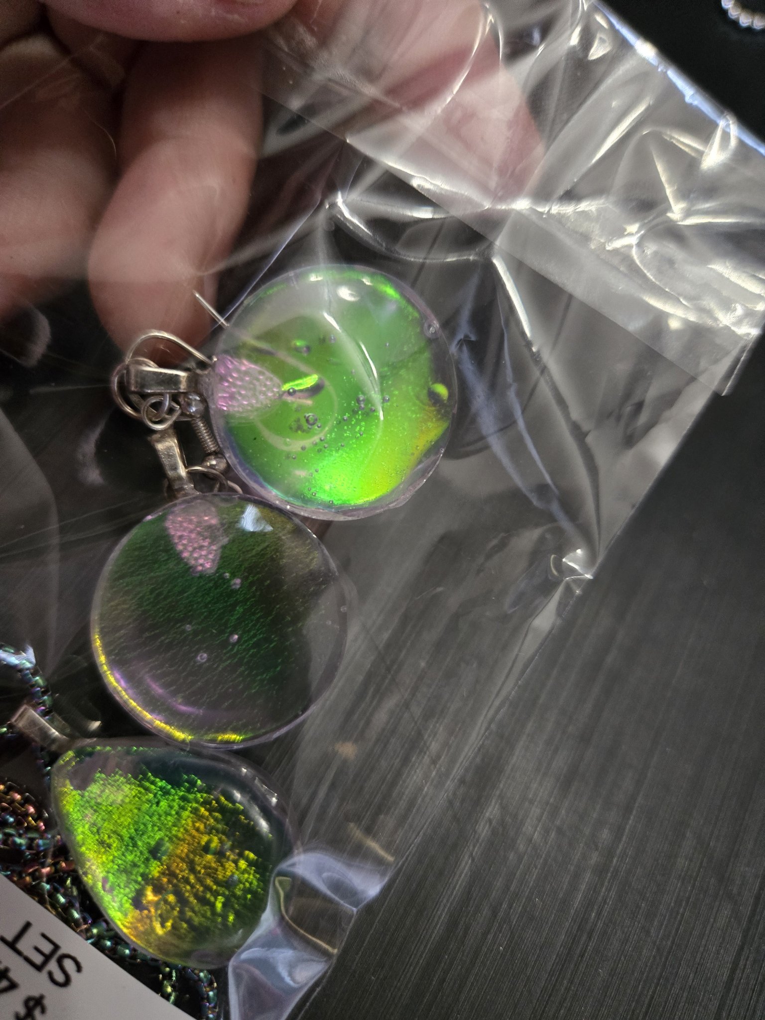Backs of the matching green-gold holographic earrings and teardrop pendant