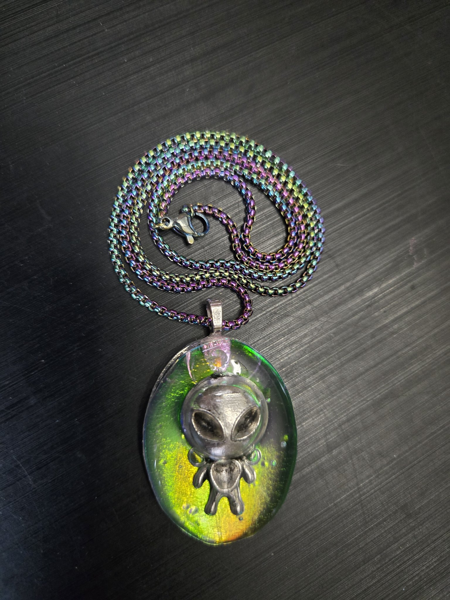 Full view of the alien grey pendant with its coiled 19-inch rainbow chain