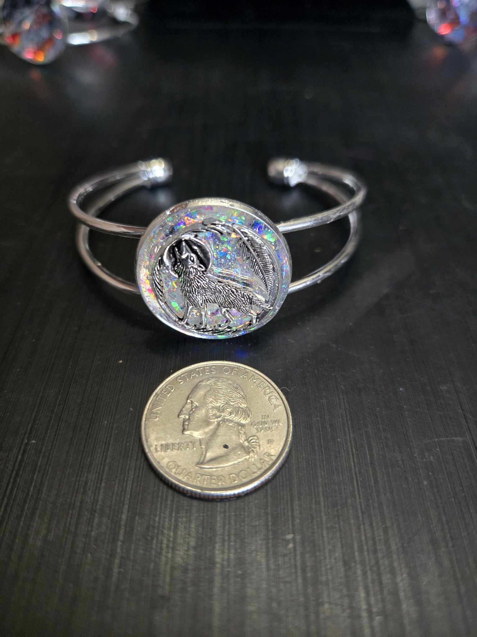 Silver-tone holographic wolf cuff bracelet beside a quarter showing the medallion is approximately one and a half inches across