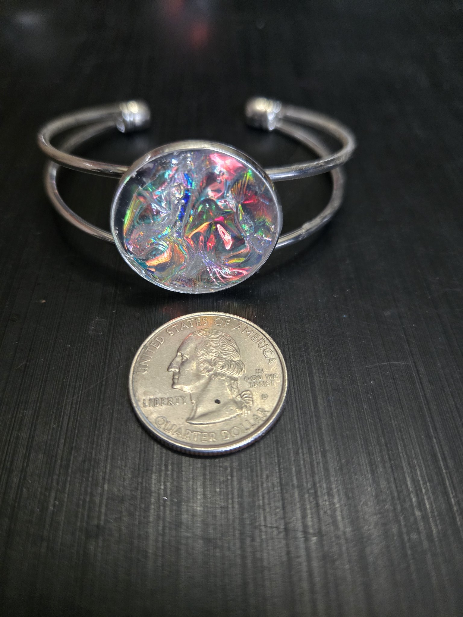 Plain holographic resin cuff bracelet beside a quarter showing the medallion is approximately one and a half inches across