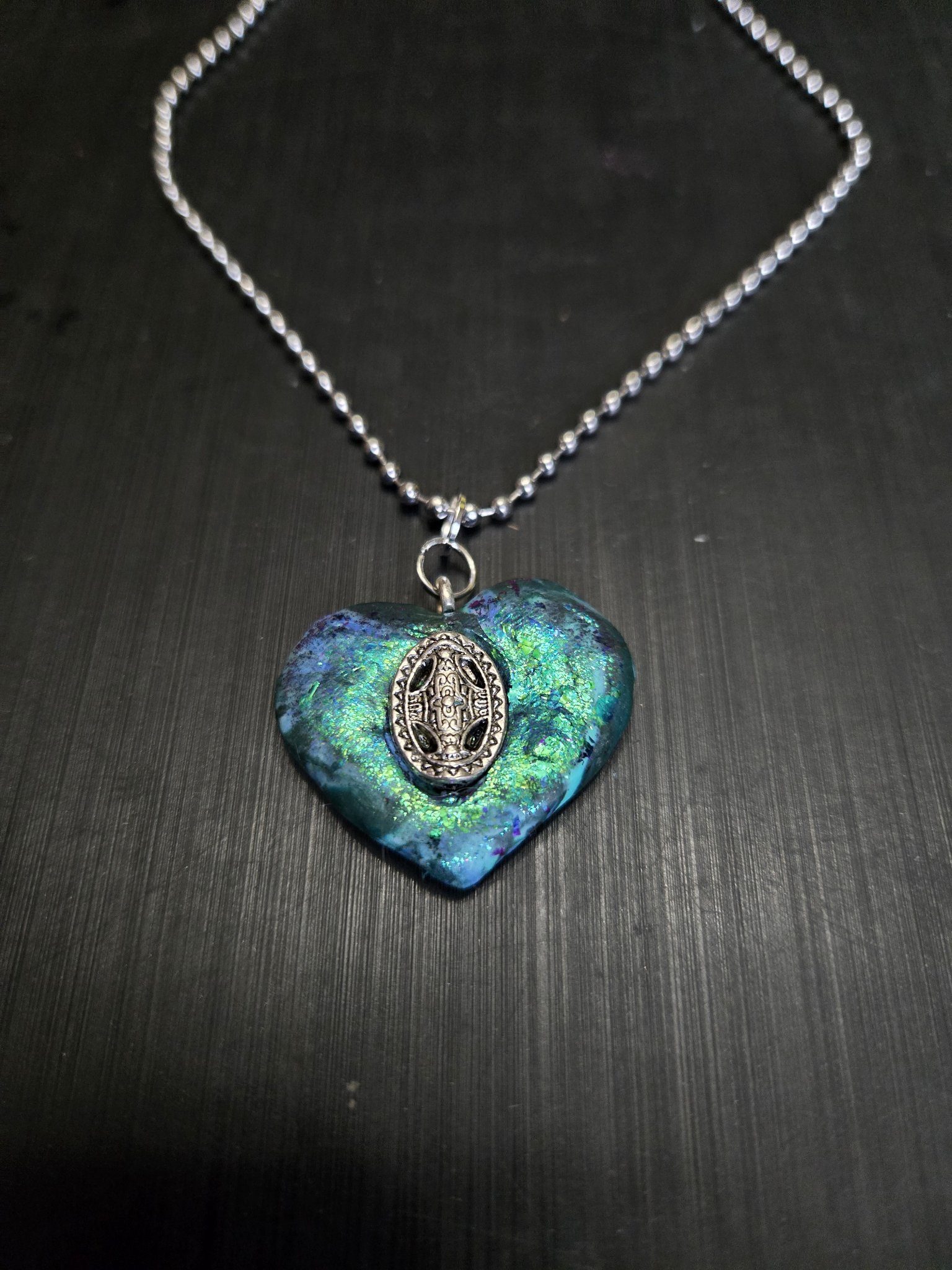 Stock 147 teal, blue, and green iridescent polymer clay heart pendant with a silver-tone Celtic-design oval medallion on a bubble chain