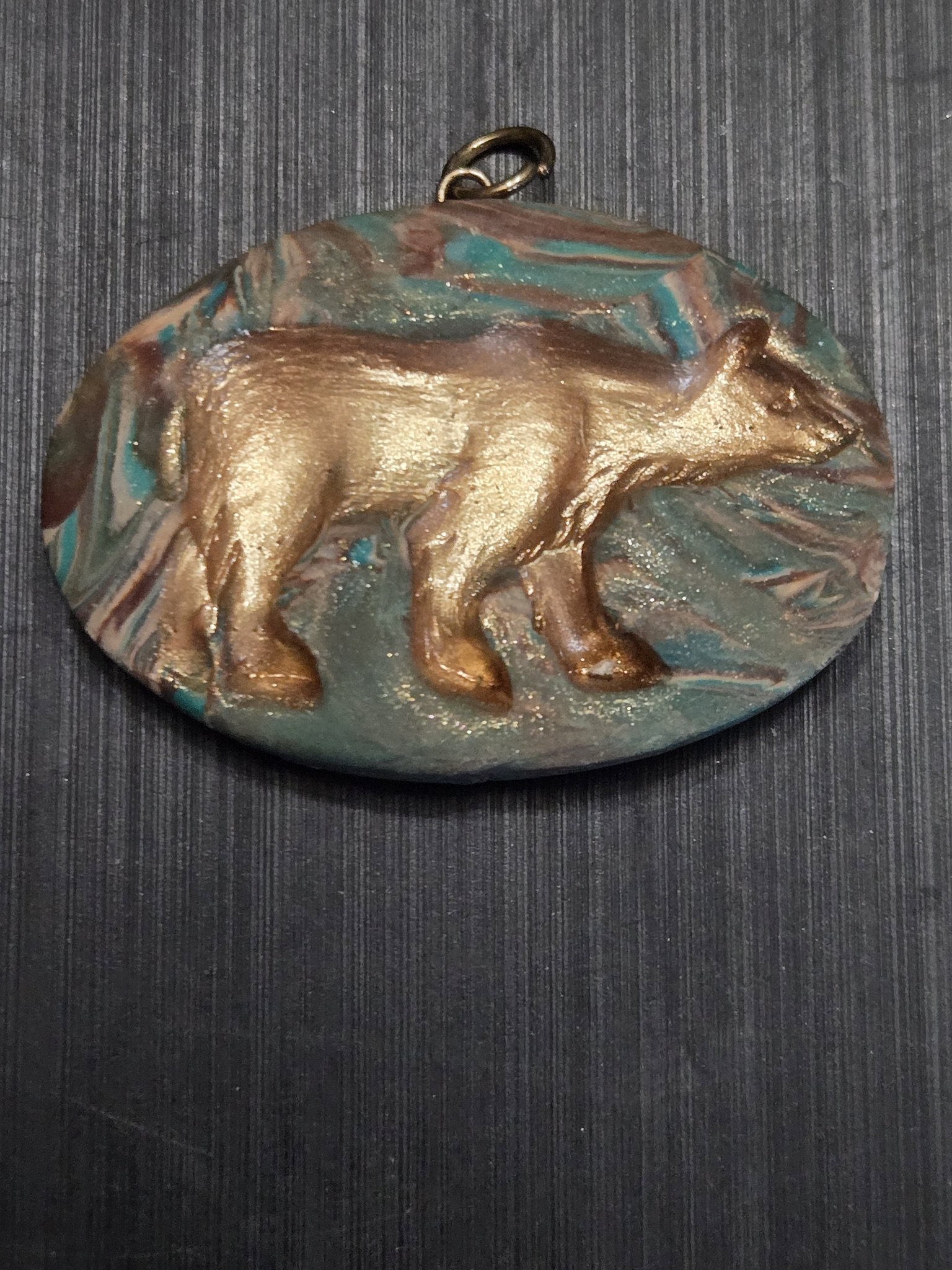 Stock 153 marbled teal and brown polymer clay oval pendant with a gold grizzly bear relief