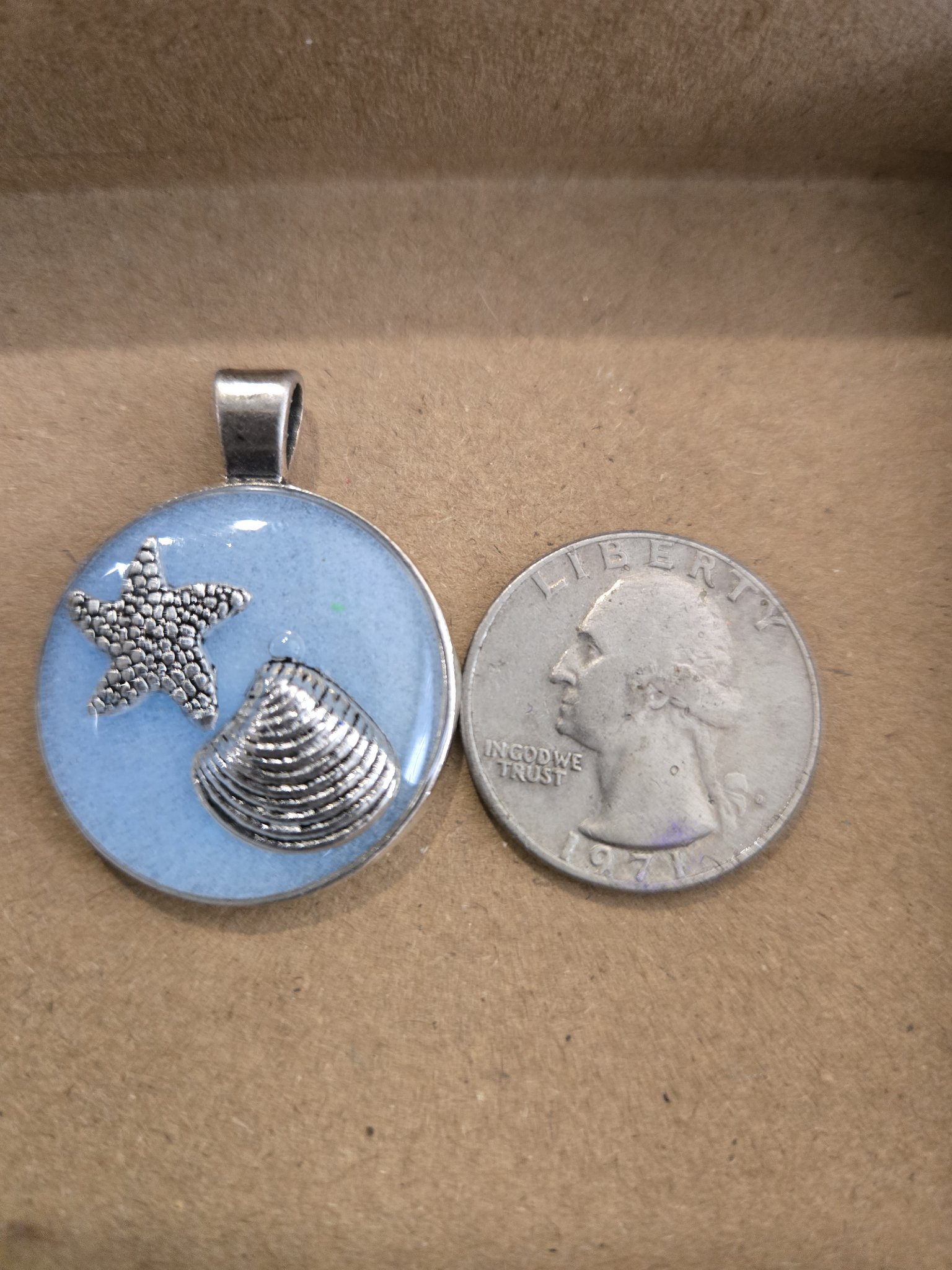 Stock 170 glow-in-the-dark beach theme pendant beside a quarter for scale