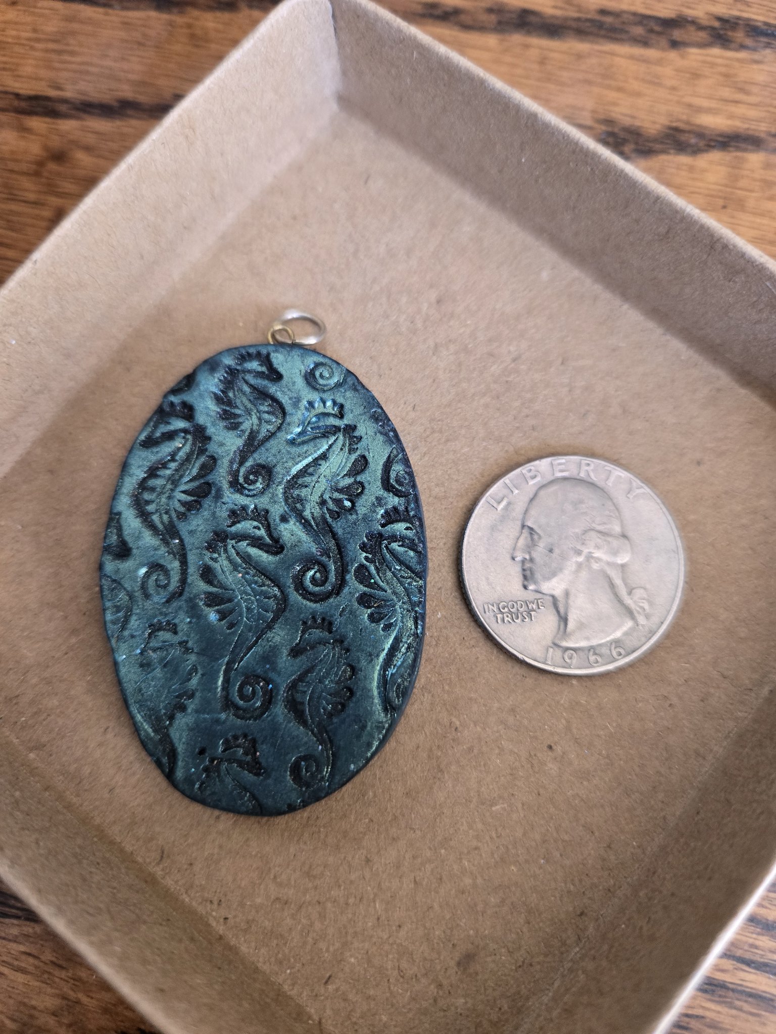 Stock 171 teal blue seahorse polymer clay pendant beside a quarter for scale