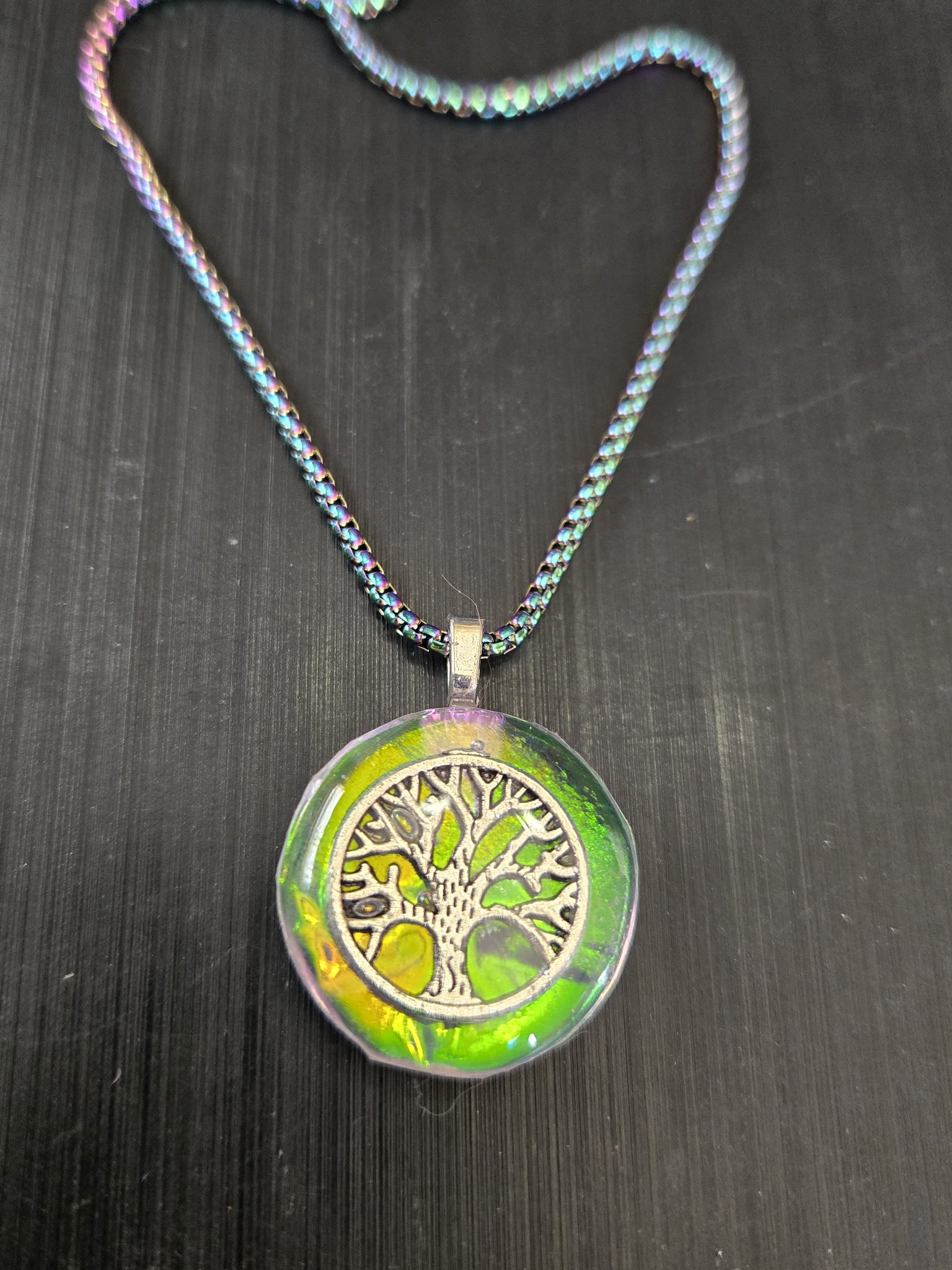 Stock 182 round green-gold holographic resin pendant with a silver-tone tree of life charm, shown from the front with its rainbow chain