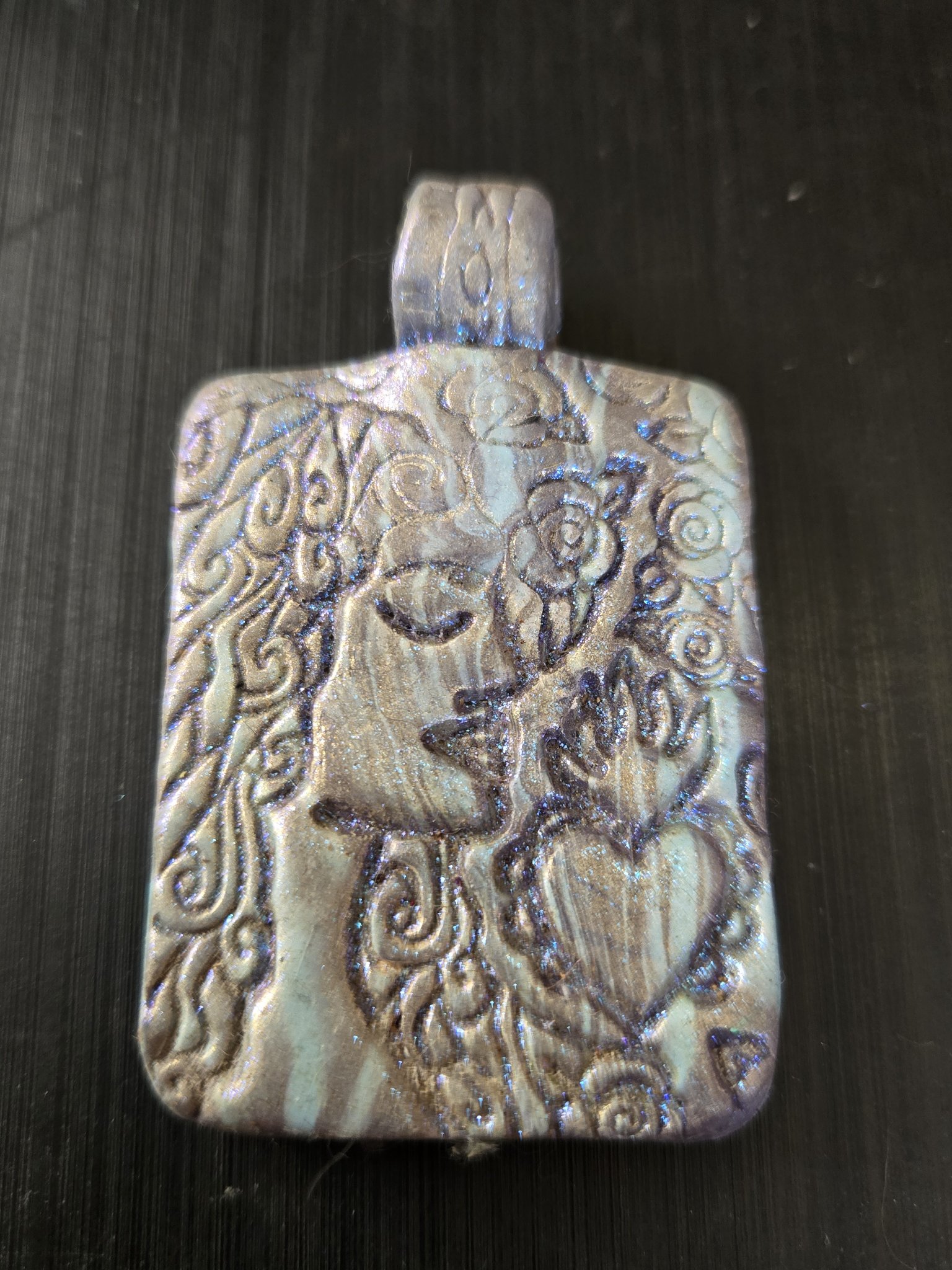 Front of stock 189 rectangular polymer clay pendant, mica-painted blue and pink with an embossed woman's face, roses, and a heart