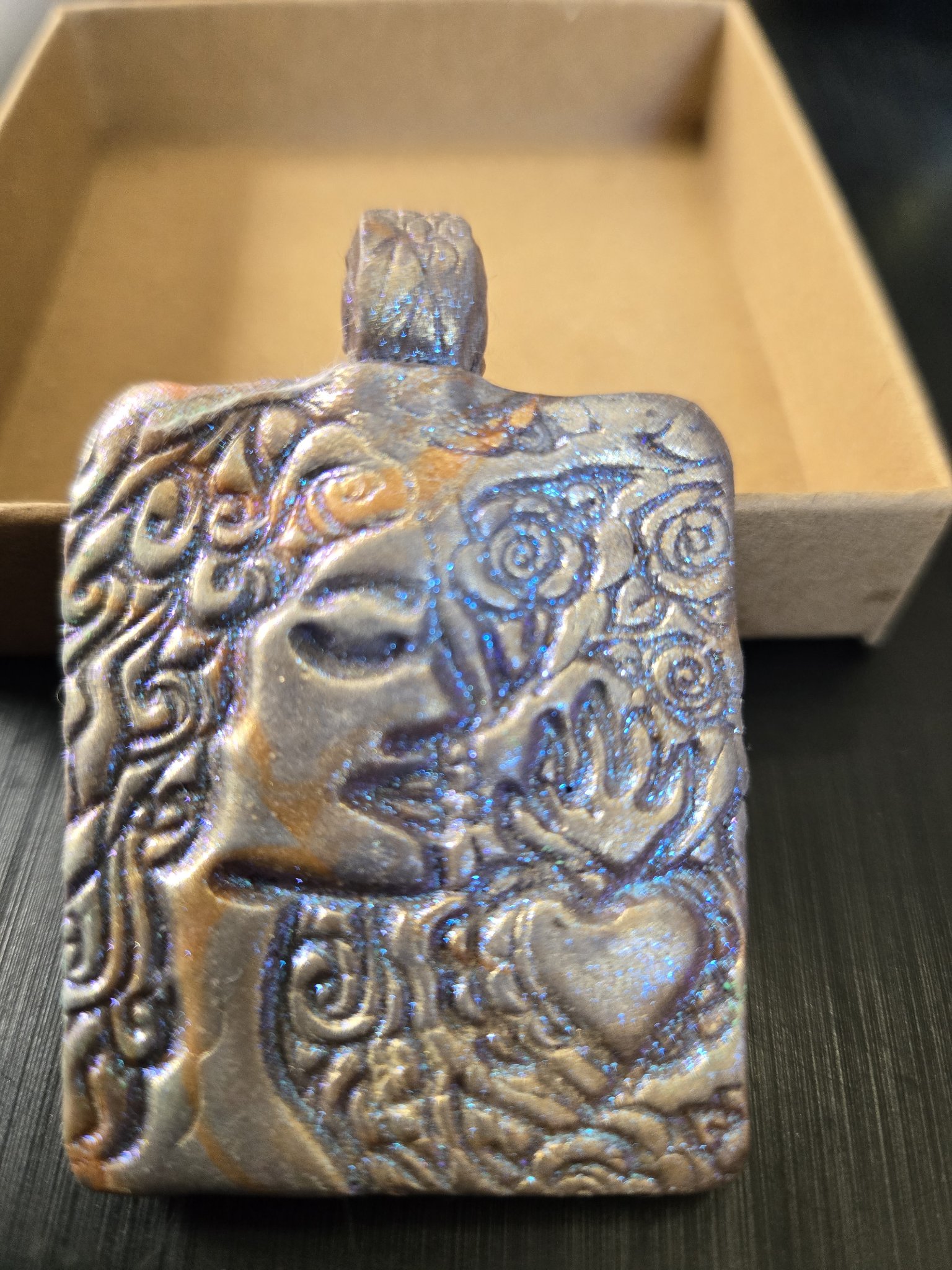 Front of stock 190 rectangular polymer clay pendant with blue mica sheen, embossed woman's face, roses, and a heart