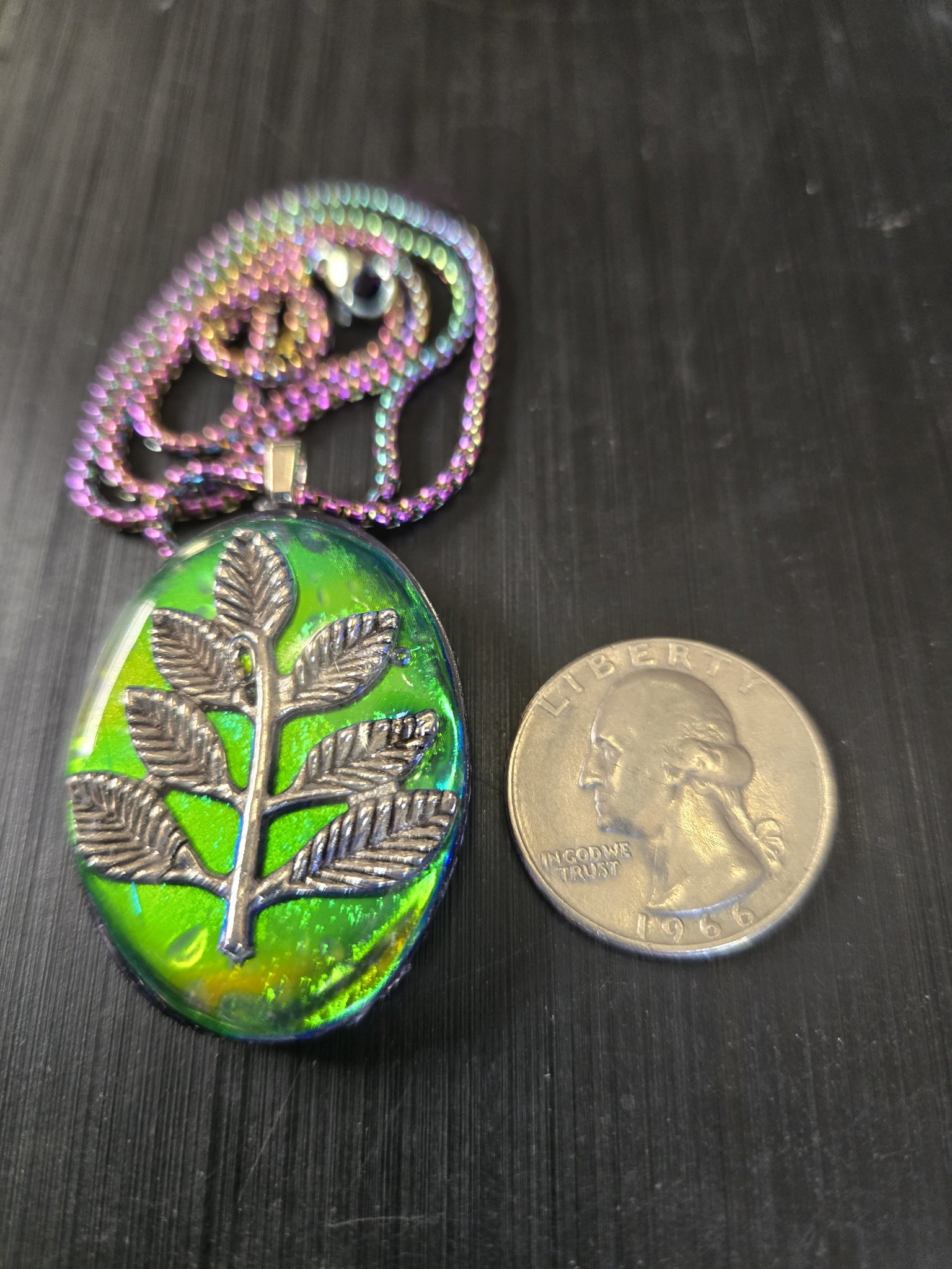 Front of stock 193 holographic branch resin pendant beside a quarter for scale