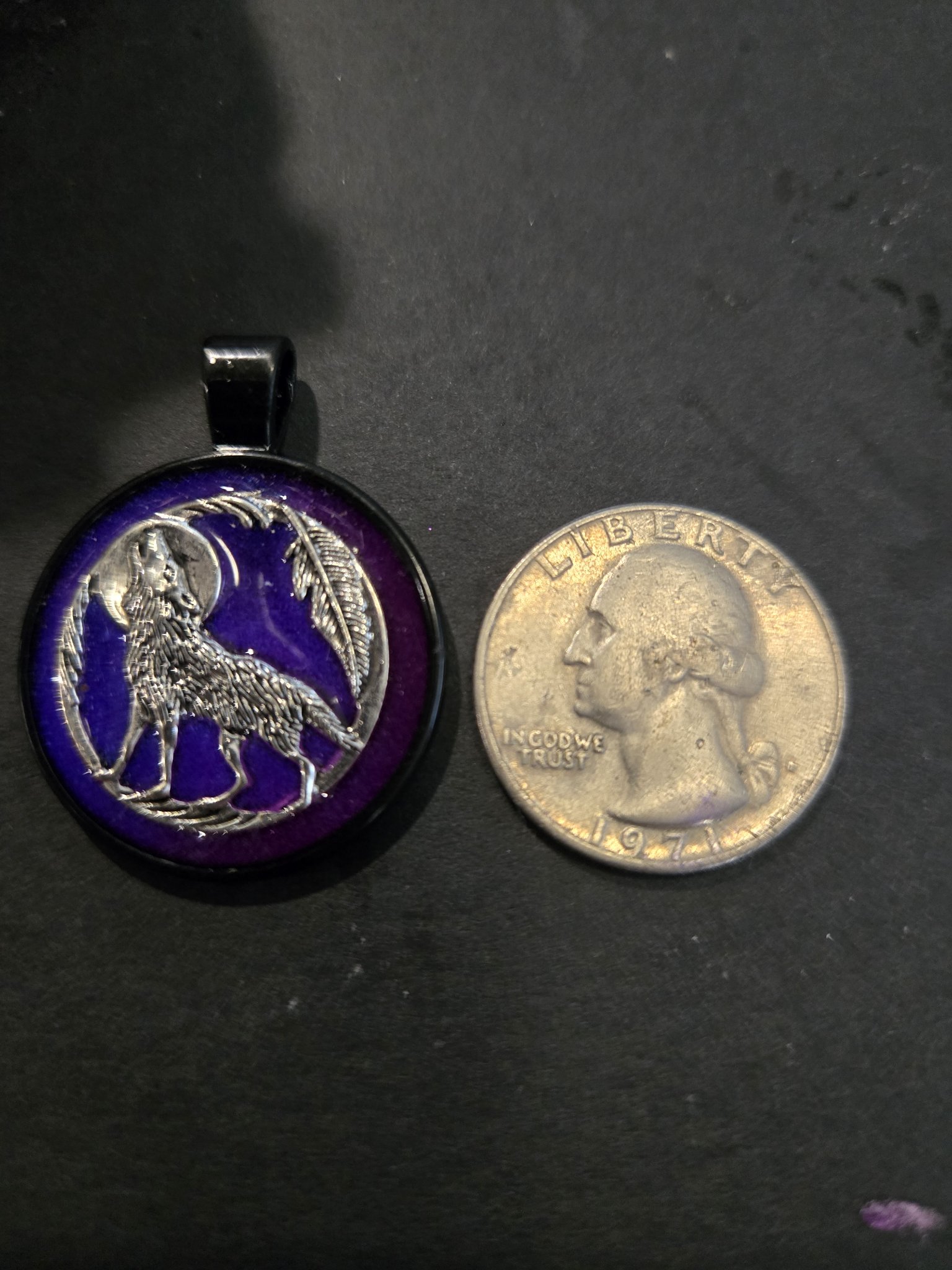 Front of stock 198 howling wolf resin pendant beside a quarter for scale