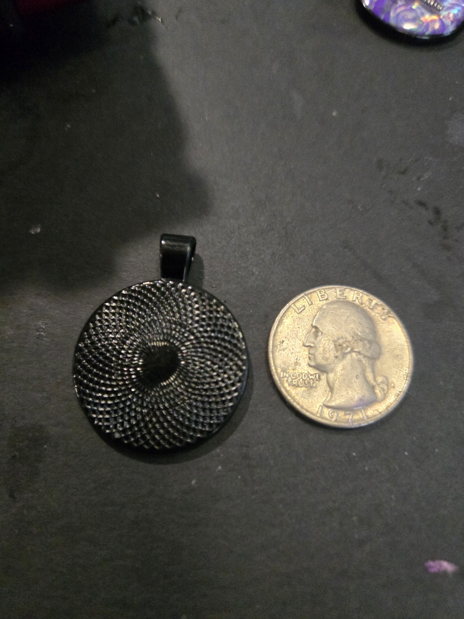 Back of stock 198 howling wolf resin pendant beside a quarter for scale