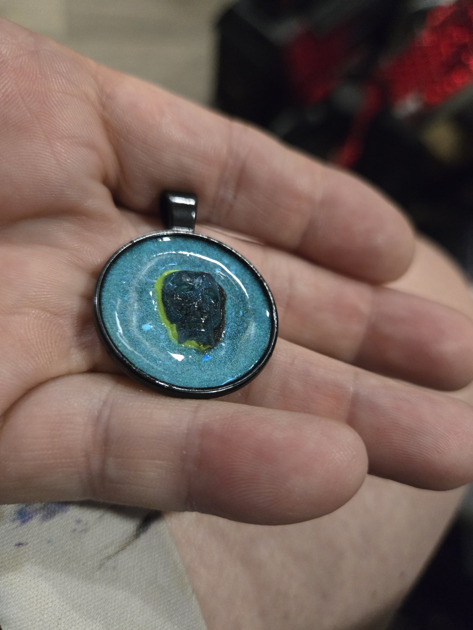 Closer front view of stock 199 crystal skull resin pendant held in a hand