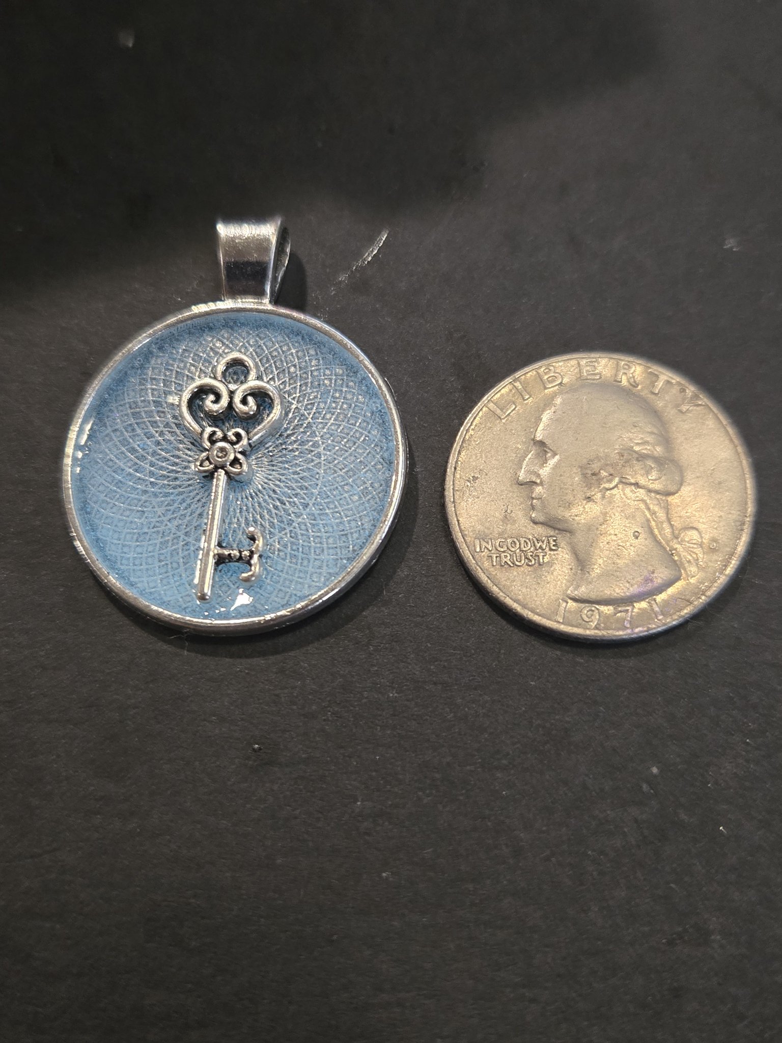 Front of stock 202 key resin pendant beside a quarter for scale