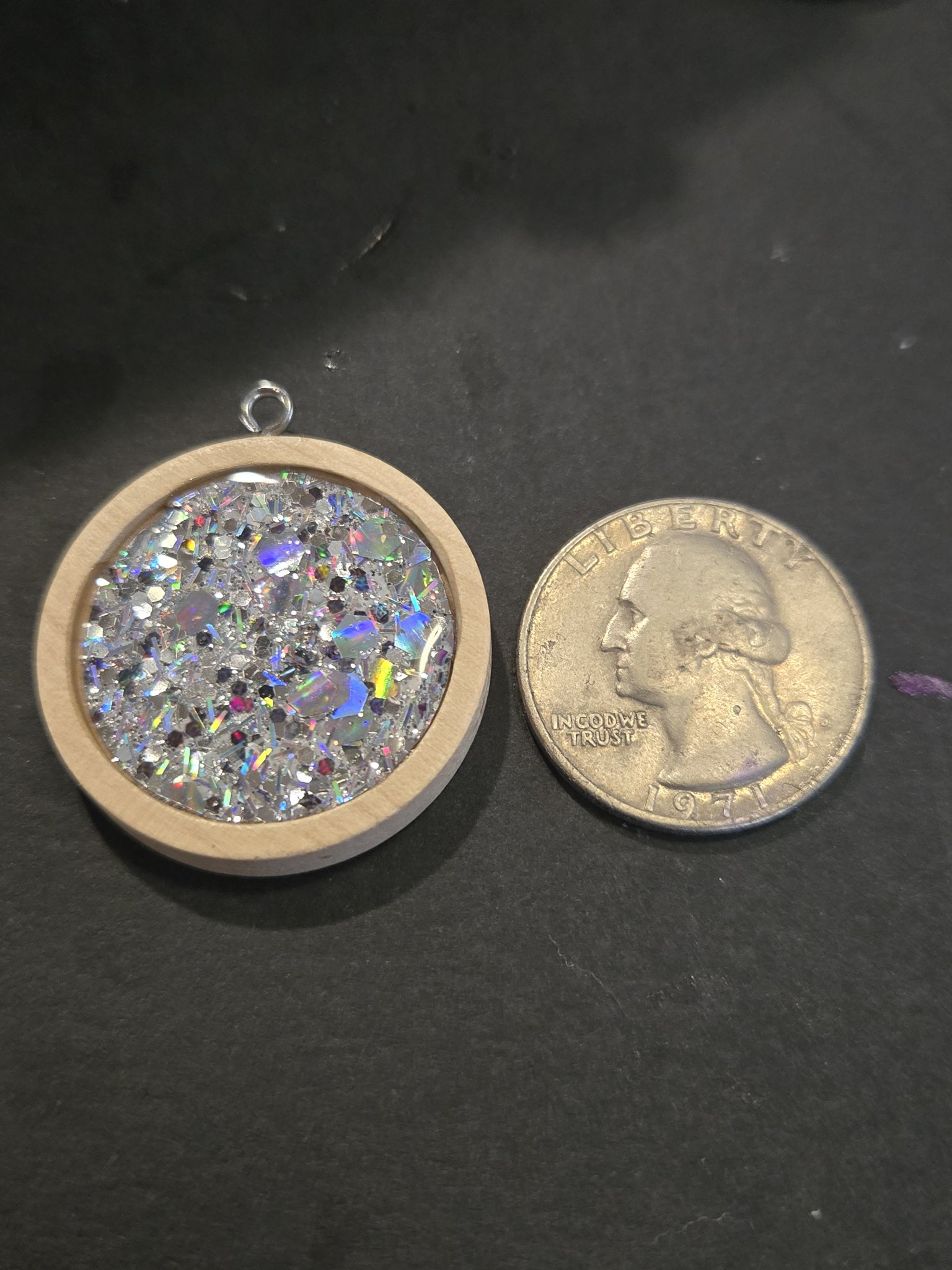 Front of stock 205 holographic iridescent resin pendant beside a quarter for scale