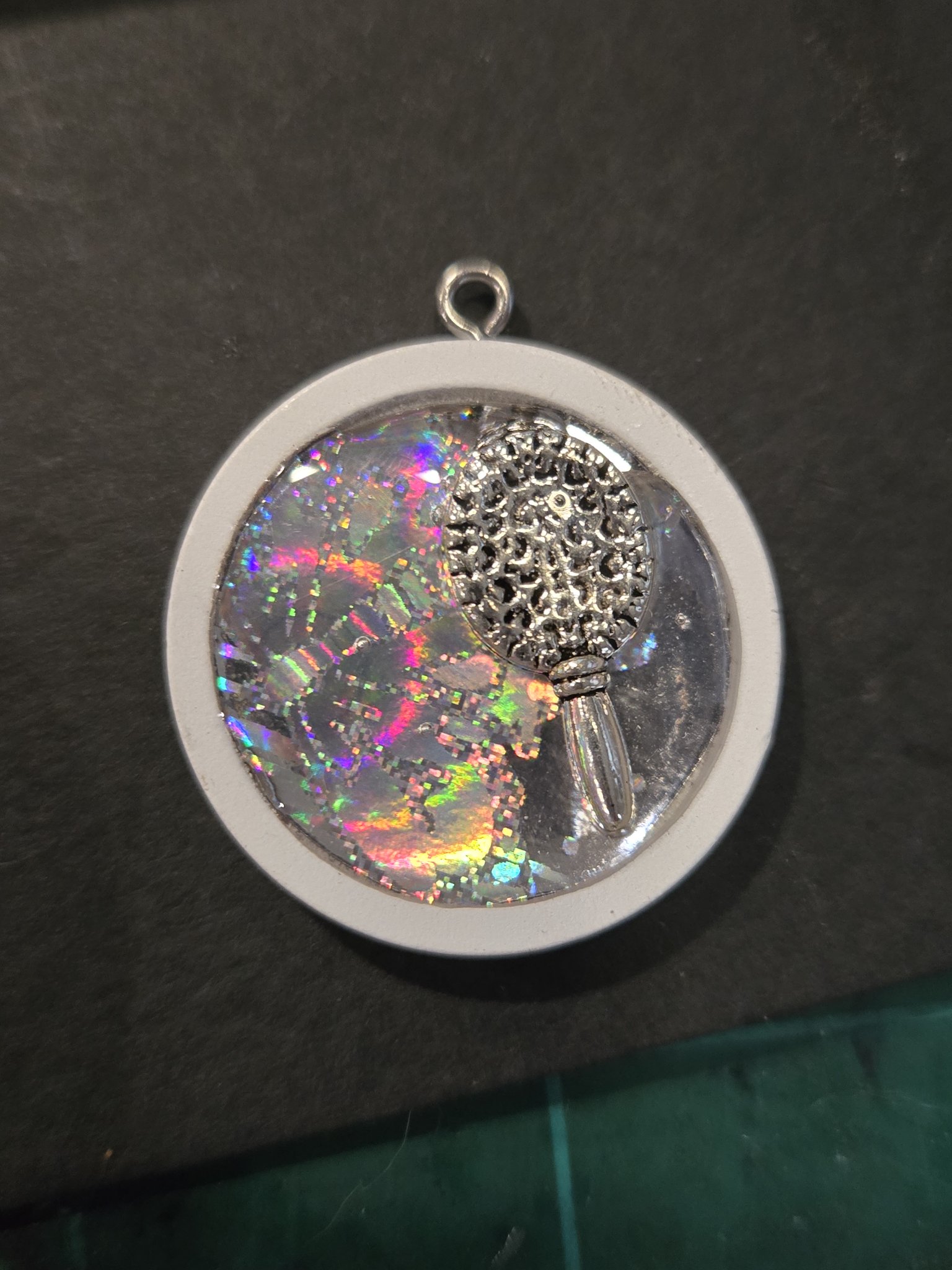 Stock 207 round holographic resin pendant with a silver-tone handmirror charm in a white wood frame, shown from the front