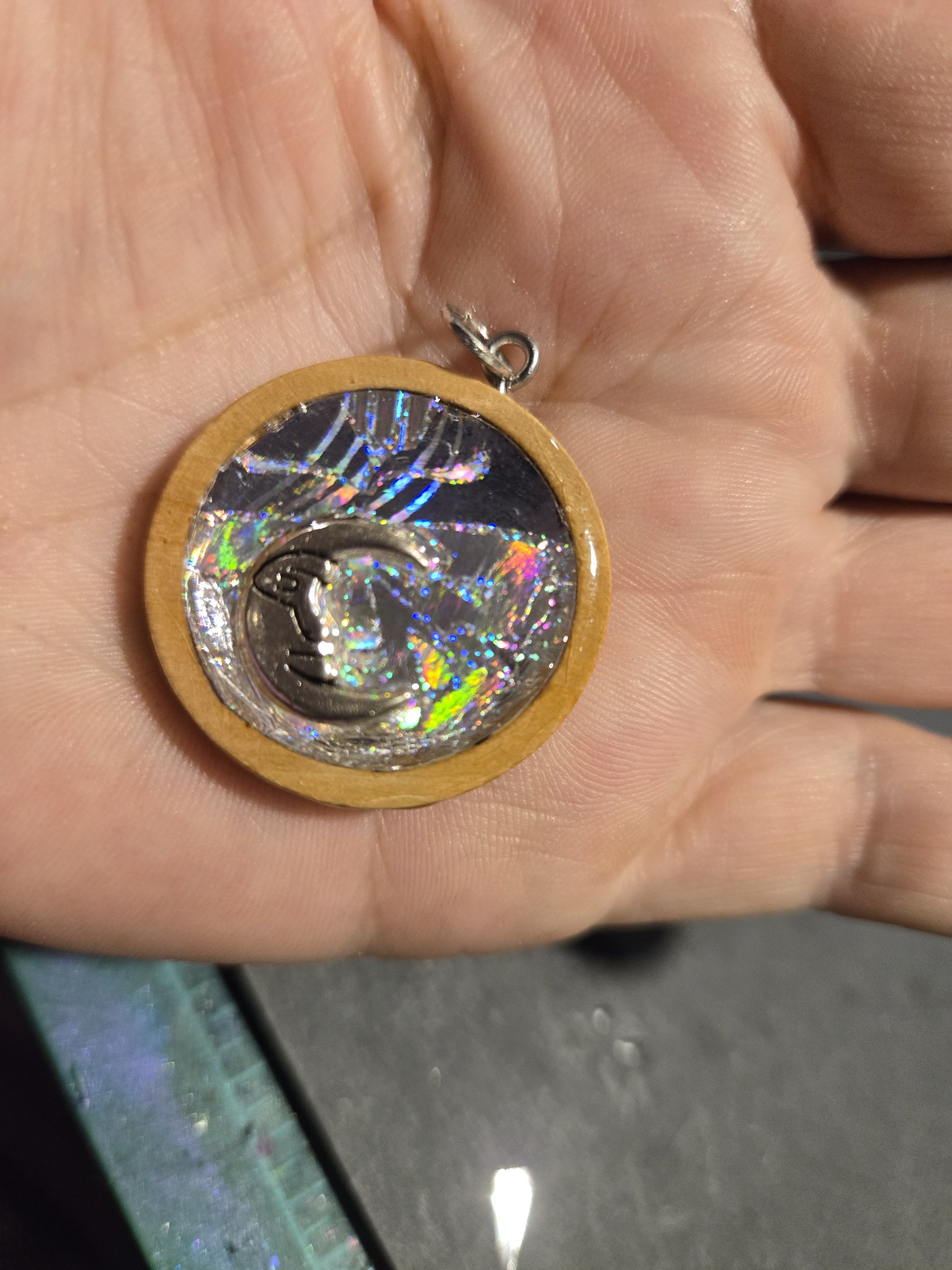 Alternate front angle of stock 209 holographic moon pendant shown in hand