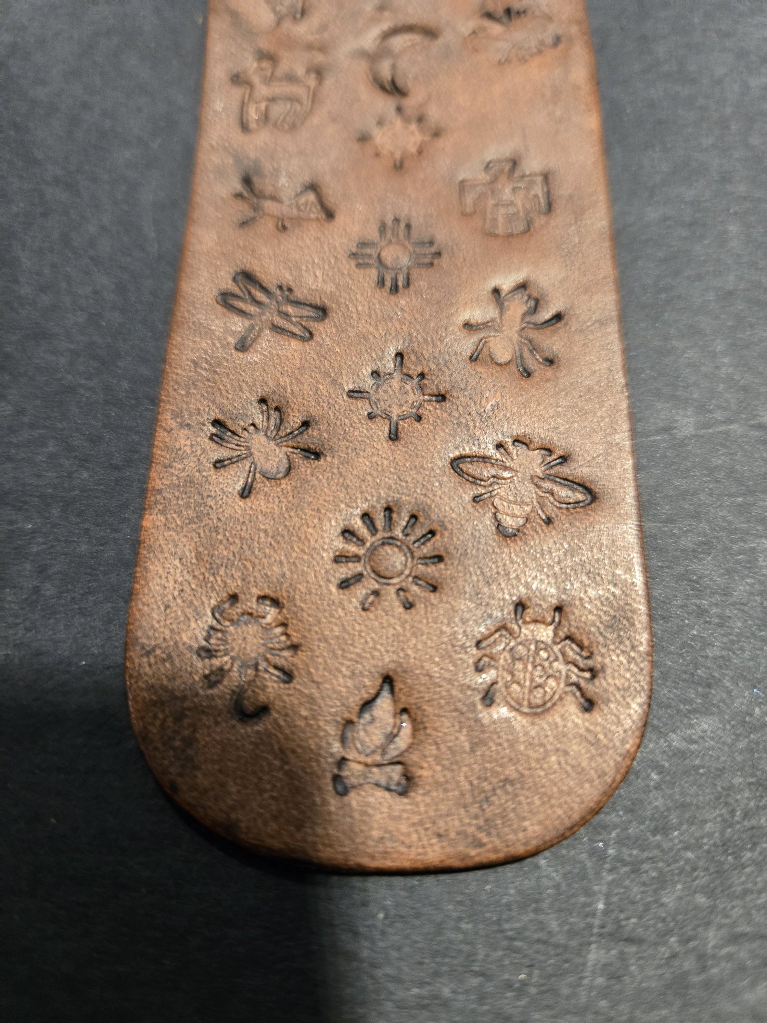 Close-up of the lower half of stock 232 showing the stamped dragonfly, sun, bee, scorpion, campfire, and ladybug
