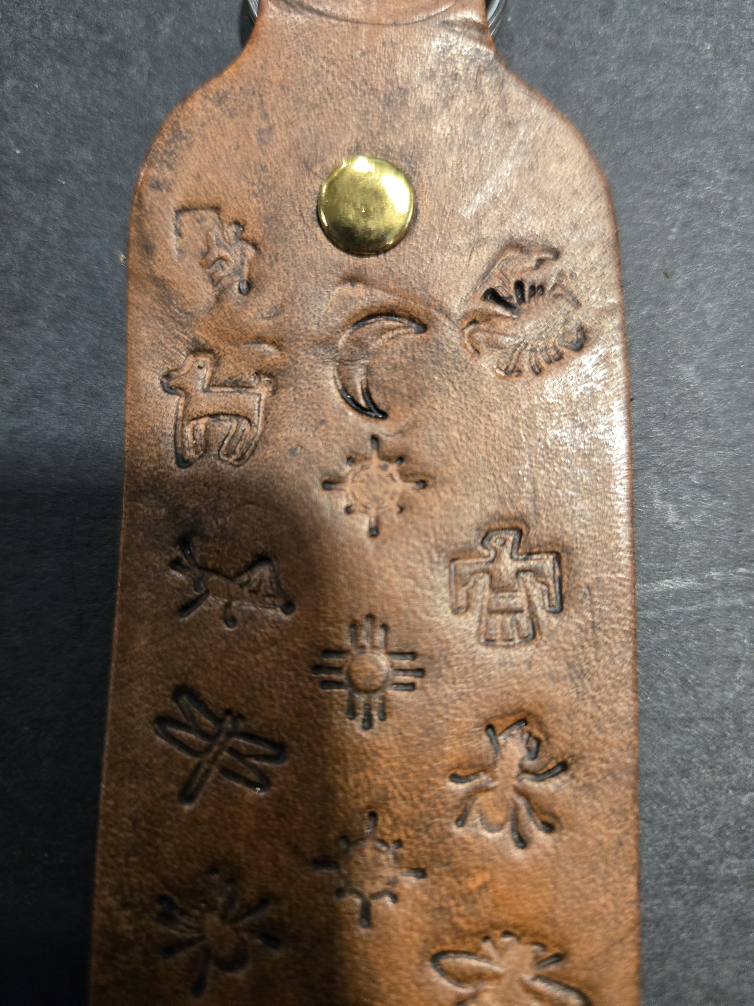 Close-up of the upper half of stock 232 showing the brass rivet and stamped dog, crescent moon, and thunderbird