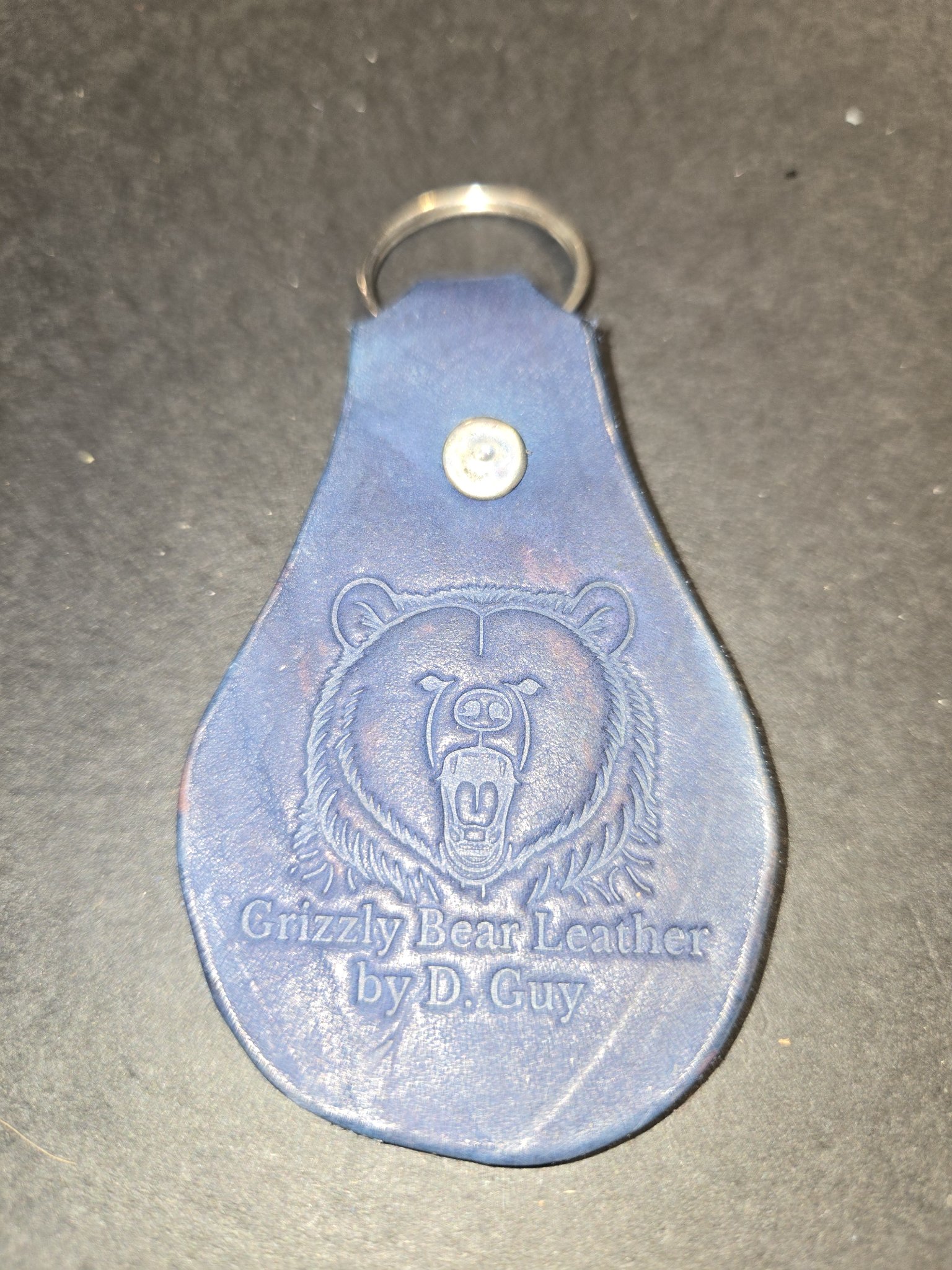 Stock 235 blue leather keychain embossed with a grizzly bear head and the words Grizzly Bear Leather by D. Guy, shown with its silver-tone rivet and split key ring