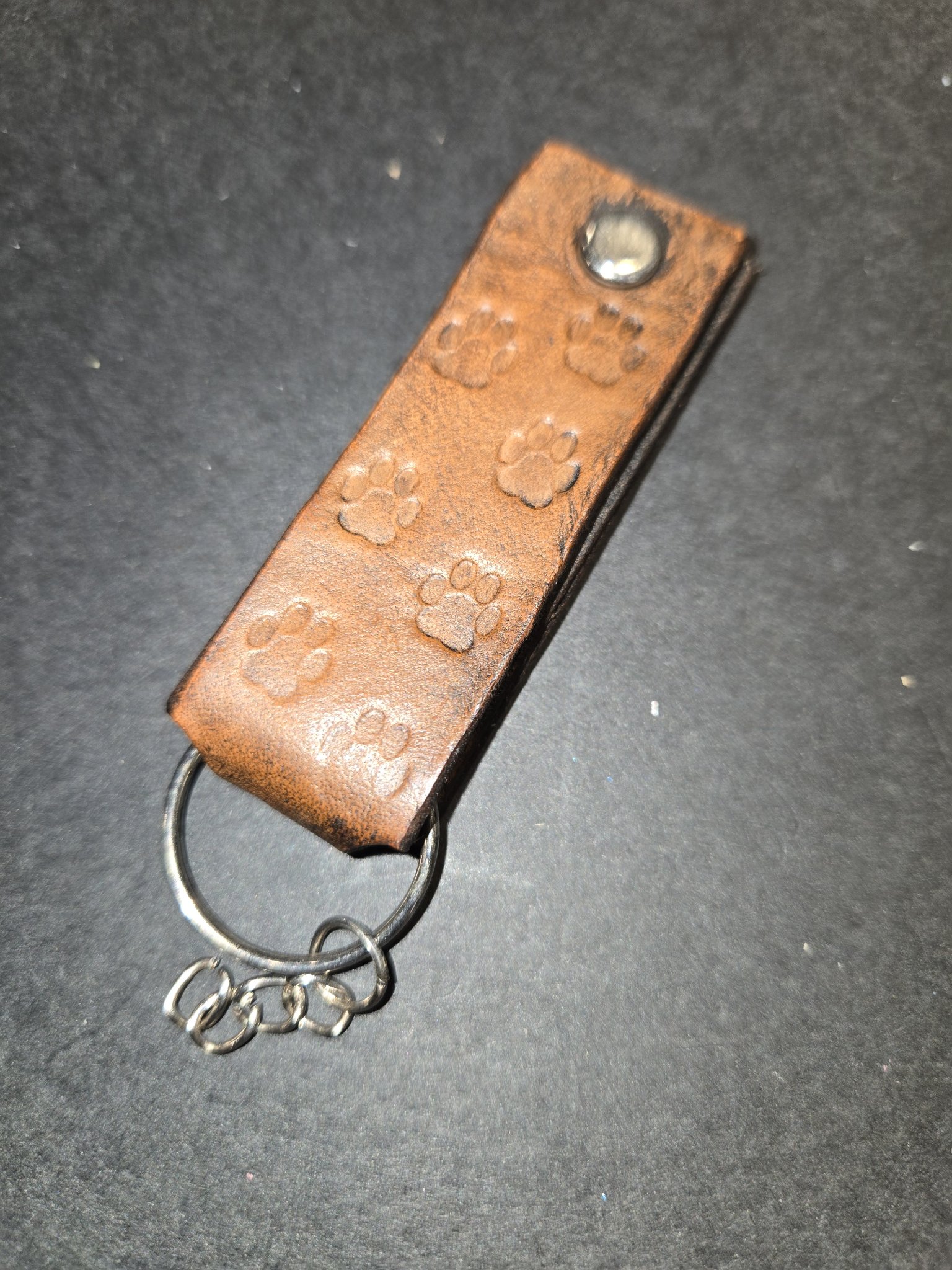Angled view of stock 237 showing the hand-stamped dog paw prints down the brown leather strap