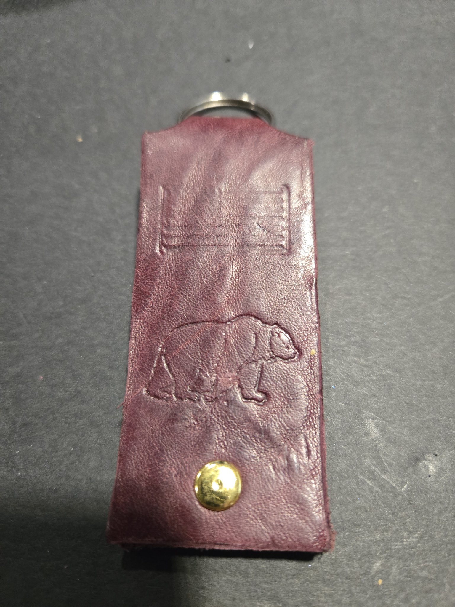 Stock 238 maroon leather keychain hand-stamped with an American flag and a grizzly bear, shown with its gold-tone rivet and split key ring