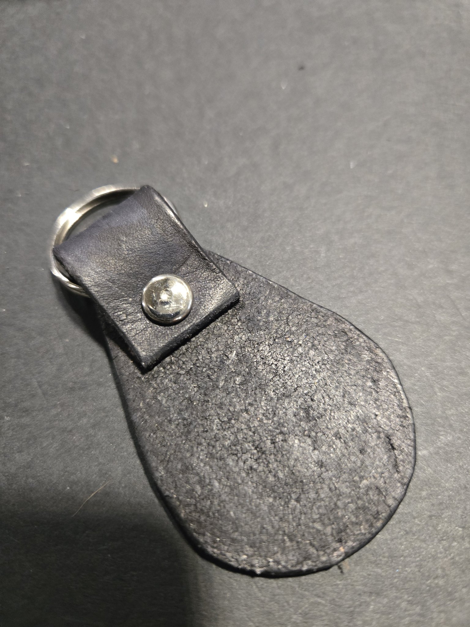 Back view of stock 241 showing the plain black leather, silver-tone rivet, and split key ring