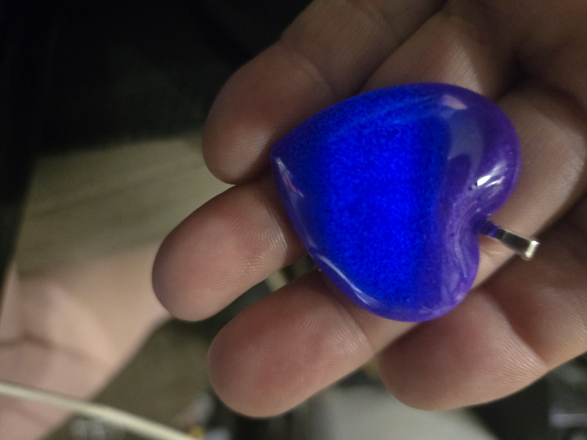 Stock 247 purple heart pendant held in a hand, glowing bright blue