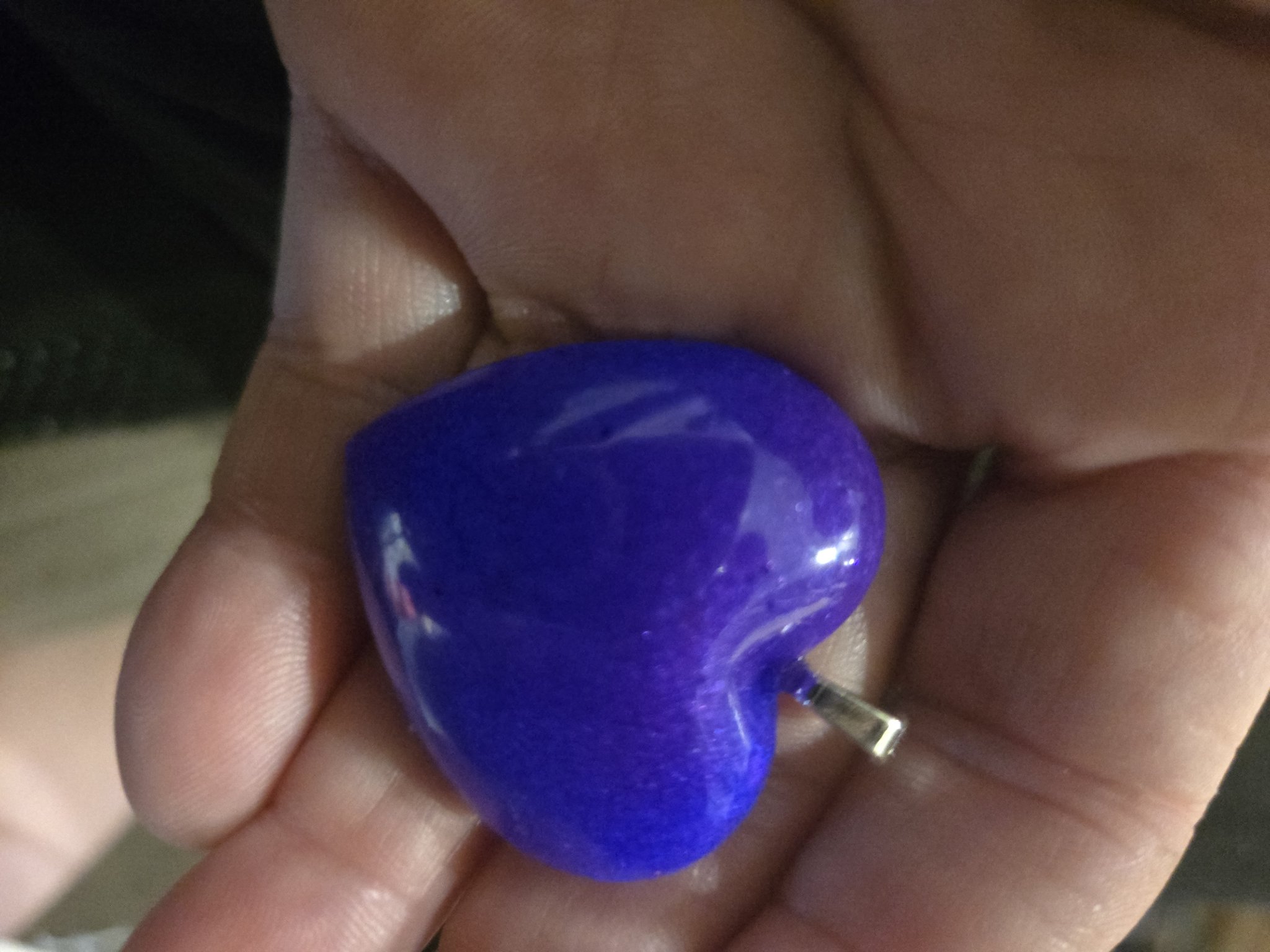 Stock 247 purple heart pendant held in an open palm, showing its glossy finish and size in hand