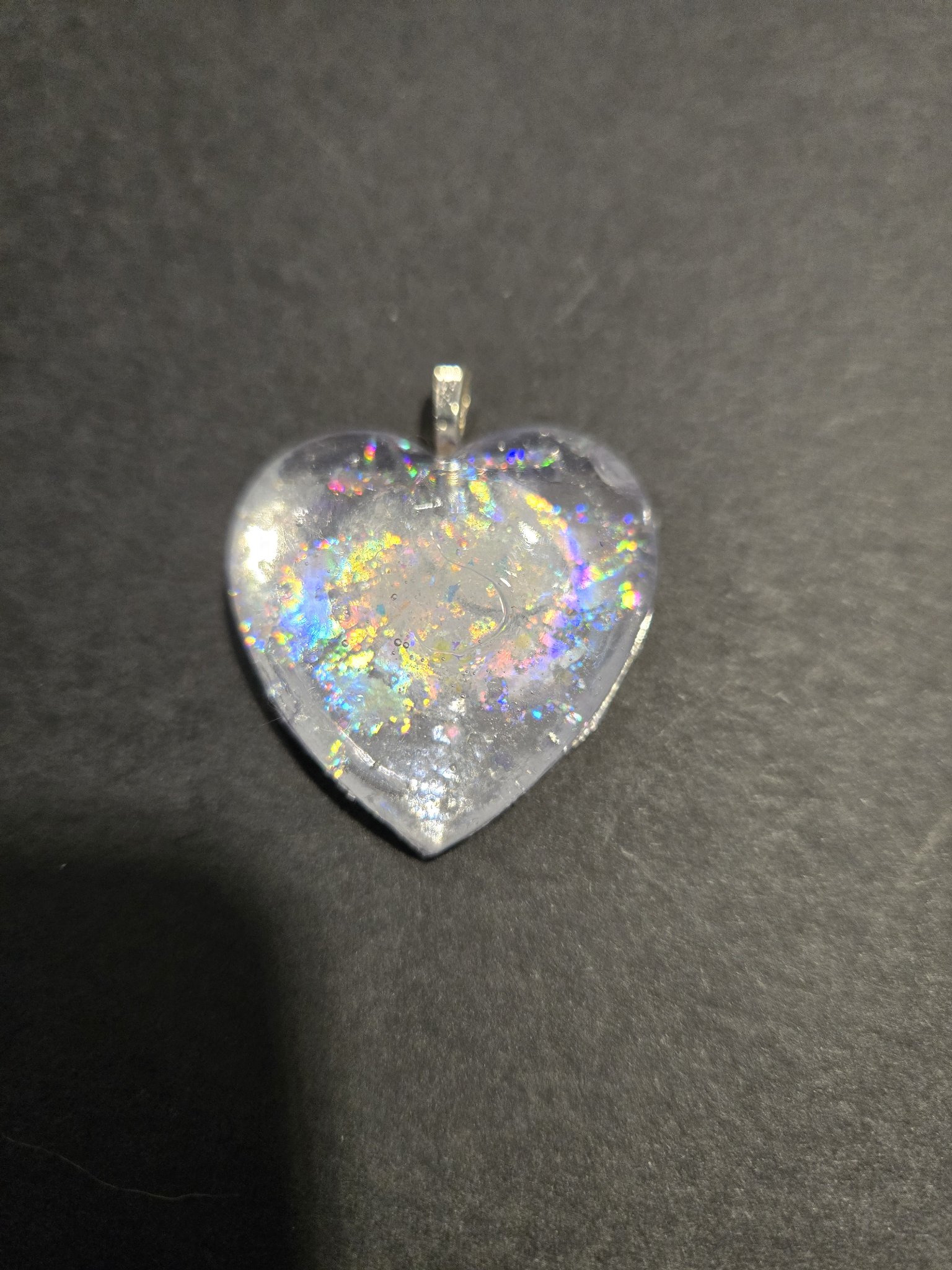 Stock 250 holographic glow heart pendant on a dark background, showing the rainbow holographic flecks in the resin