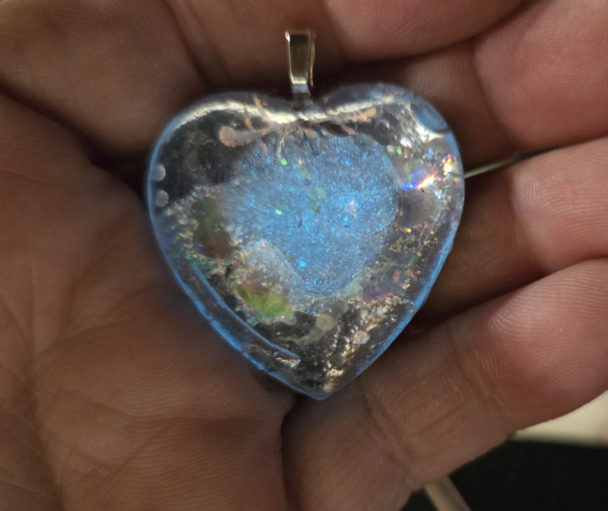Stock 250 holographic glow heart pendant held in a hand at an angle, showing the holographic sparkle