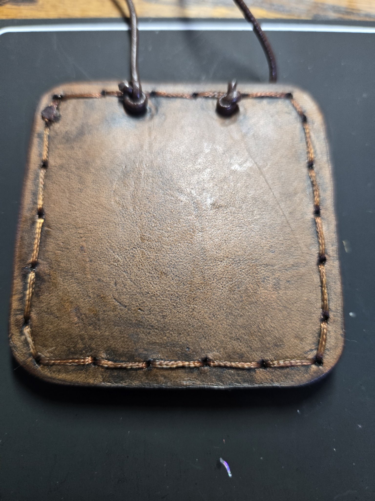 Back of the vegetable-tanned leather turtle pendant showing the hand-sewn border