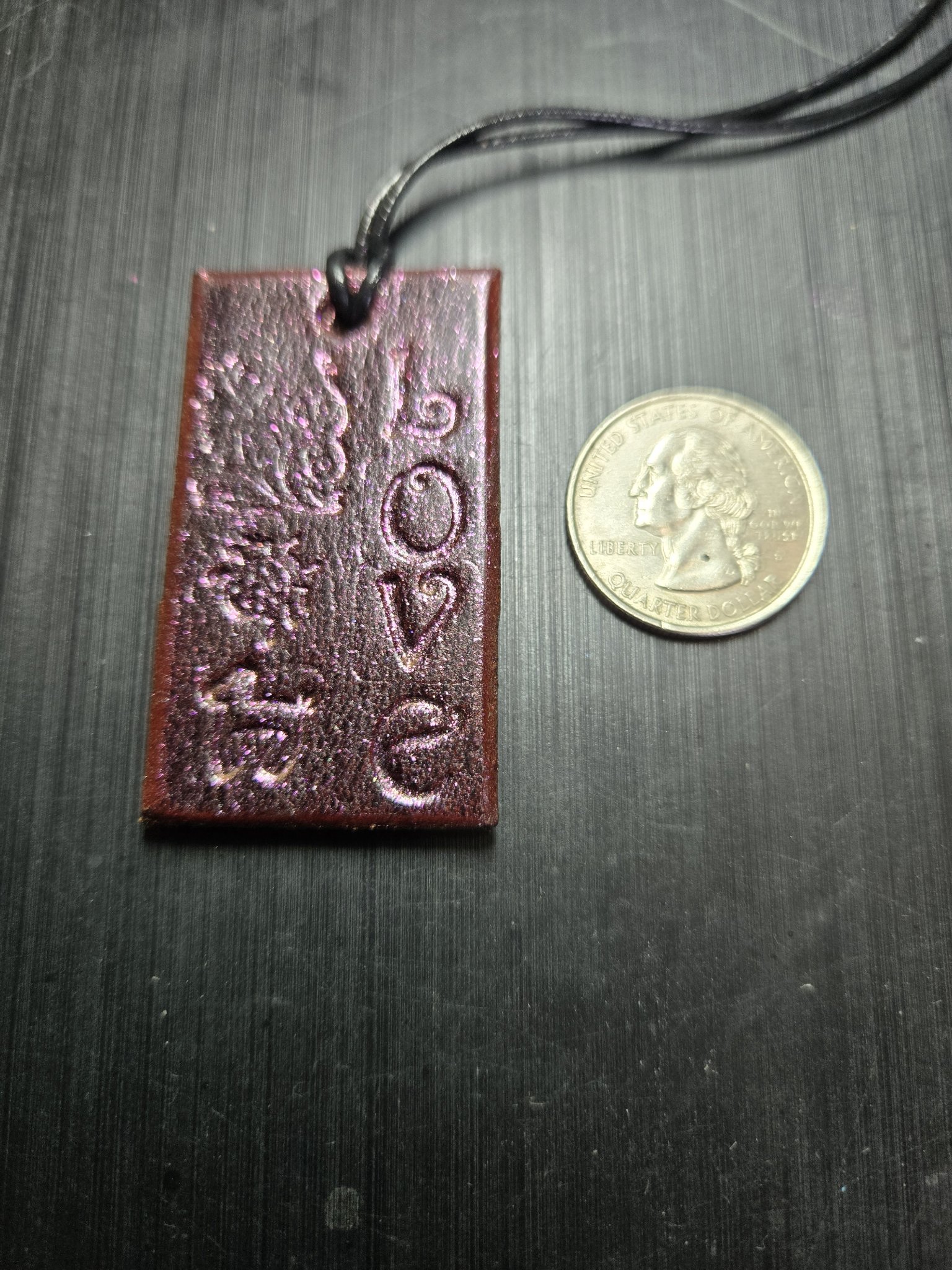 Front of the pink sparkle leather LOVE pendant beside a quarter for scale