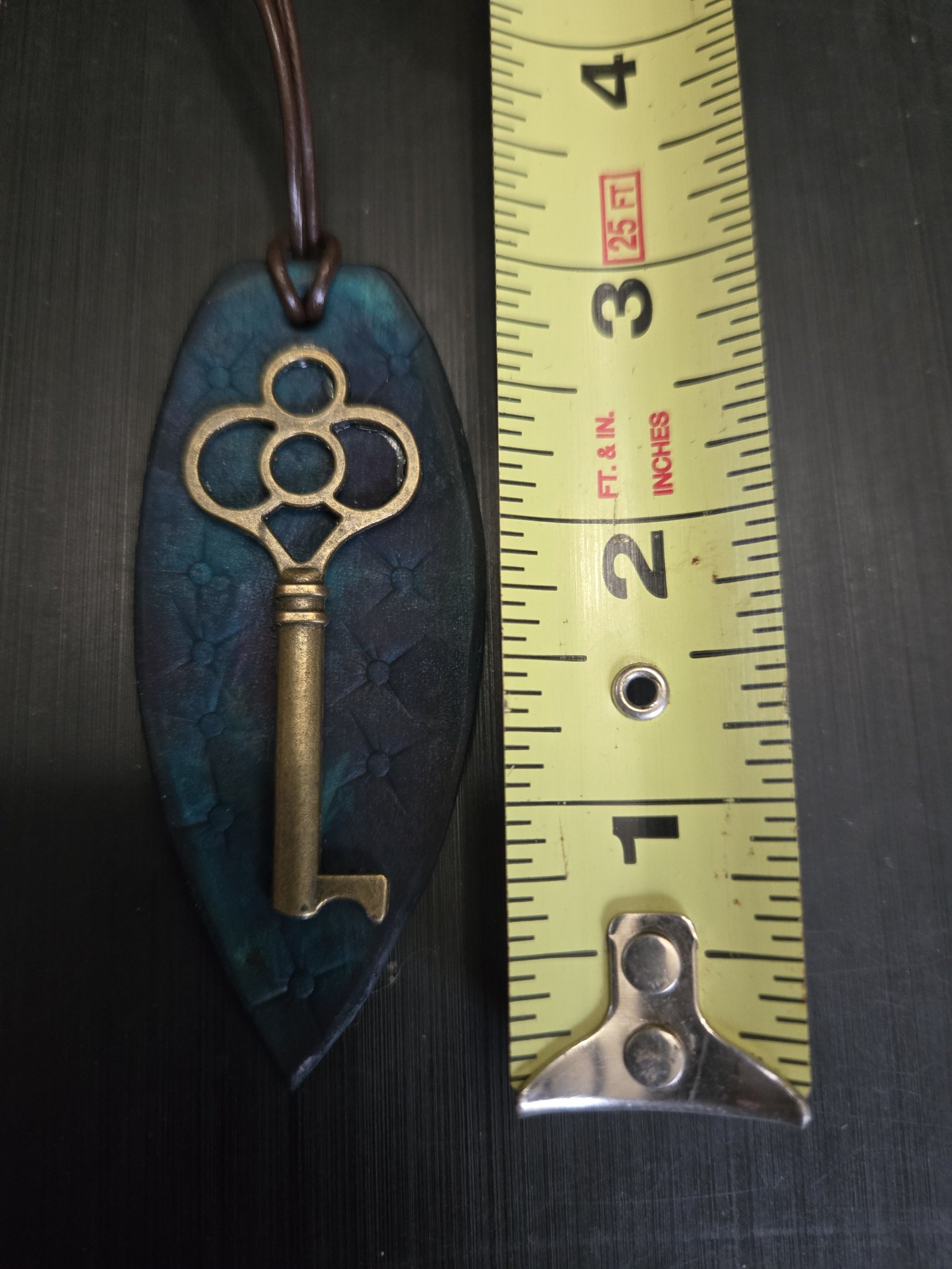 Stock 144 teal leather key pendant beside a tape measure showing it is approximately three and a half inches long