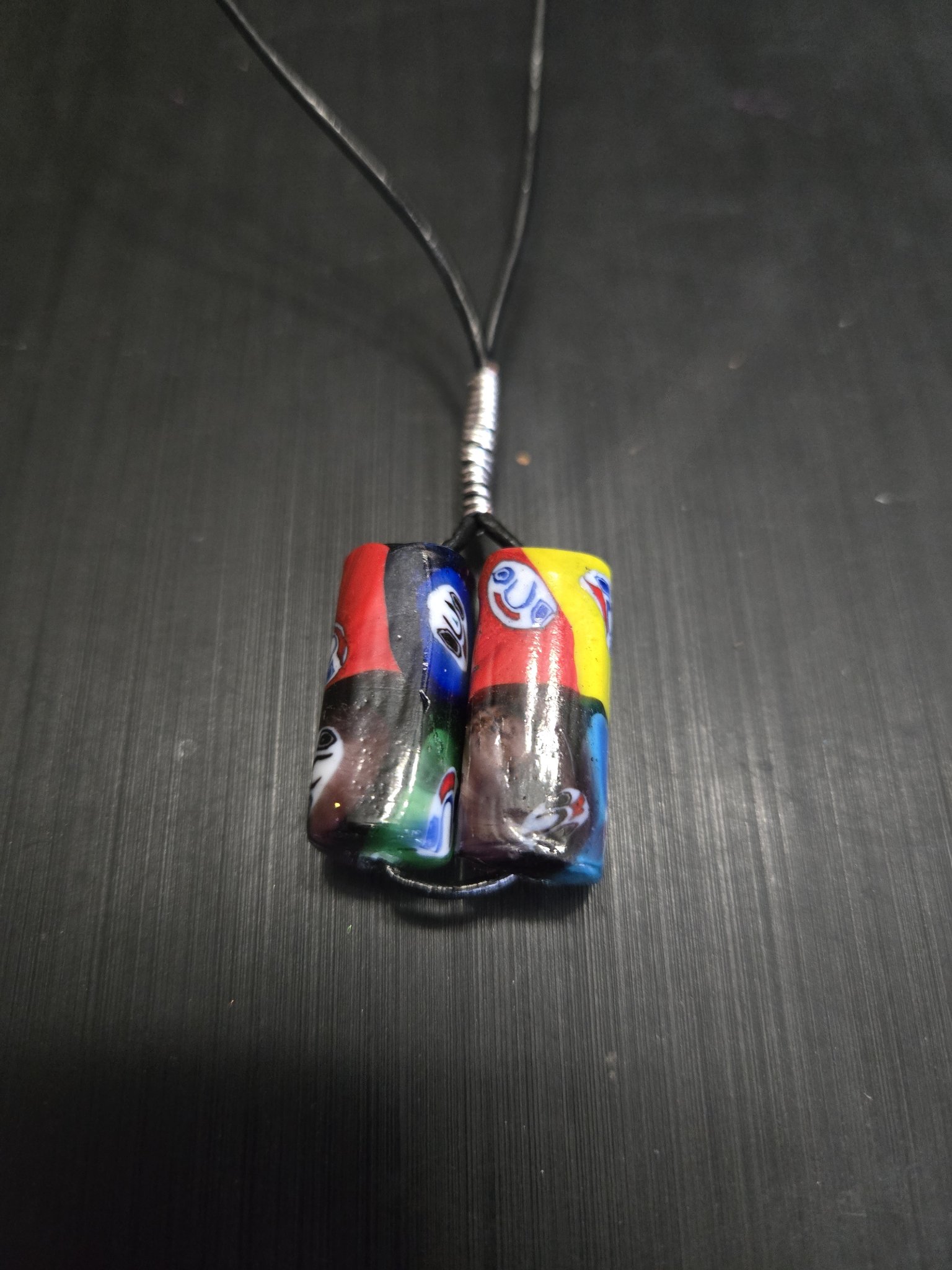 Stock 145 necklace with colorful red, blue, yellow, and green handmade decorative beads on a black leather cord